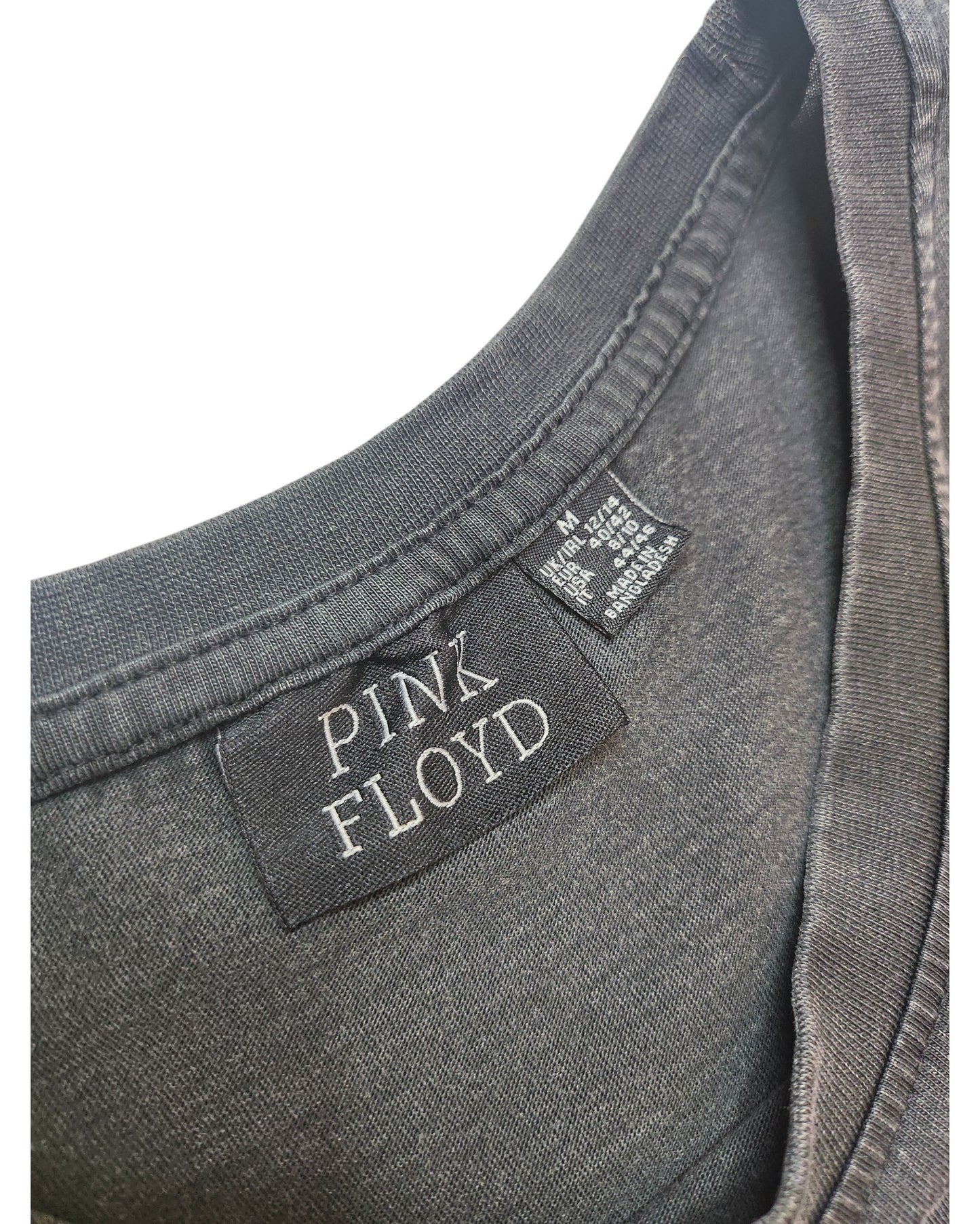 Close-up of a grey Pink Floyd T-shirt dress collar by Primark, featuring a PINK FLOYD fabric label and a care tag showing it’s made from upcycled materials for eco-friendly breastfeeding and pumping. Size M (UK12/14).
