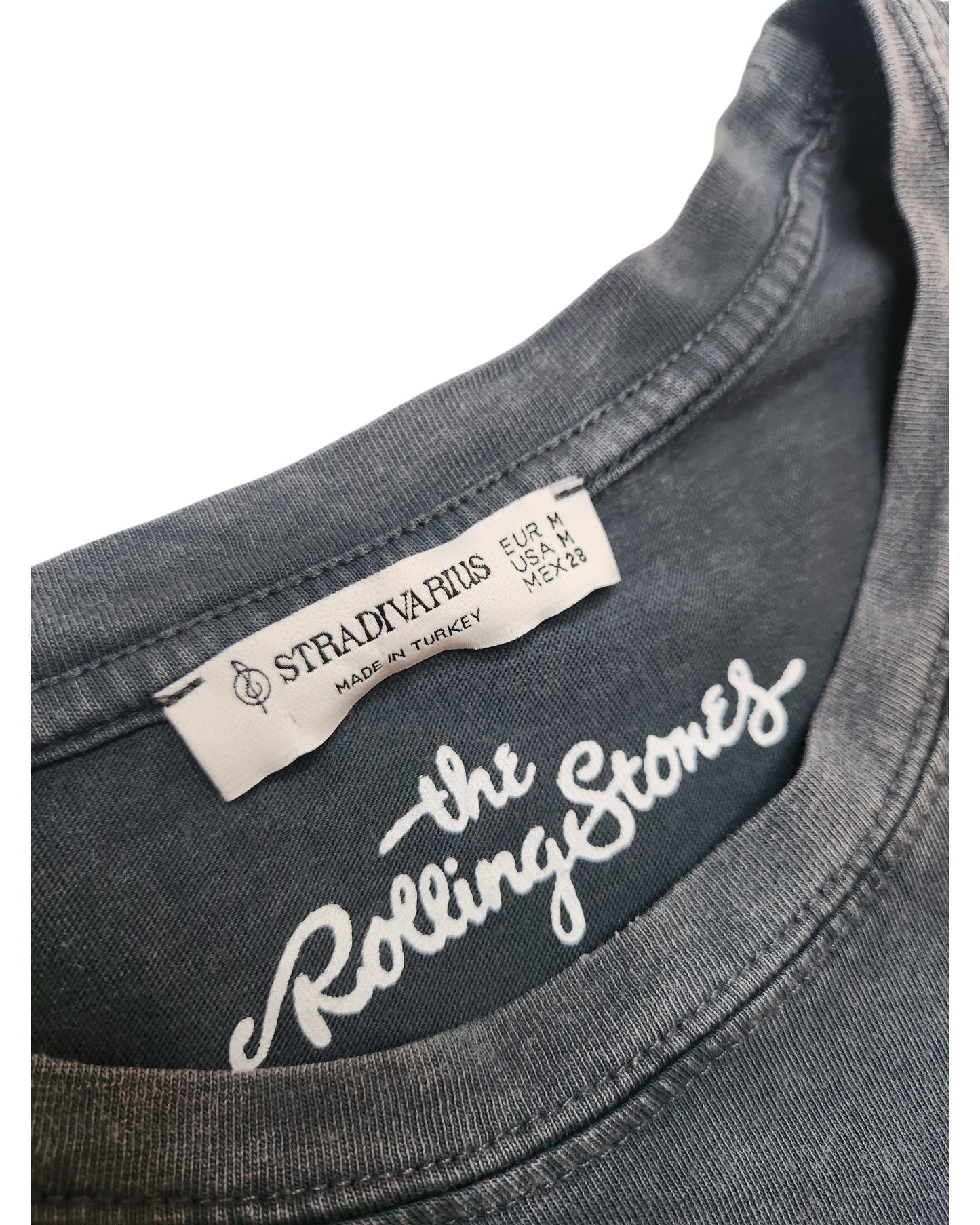 Close-up of an upcycled Stradivarius Rolling Stones grey/leopard band nursing & pumping T-shirt (M), showing collar with fabric label STRADIVARIUS Made in Turkey plus The Rolling Stones printed inside in white.