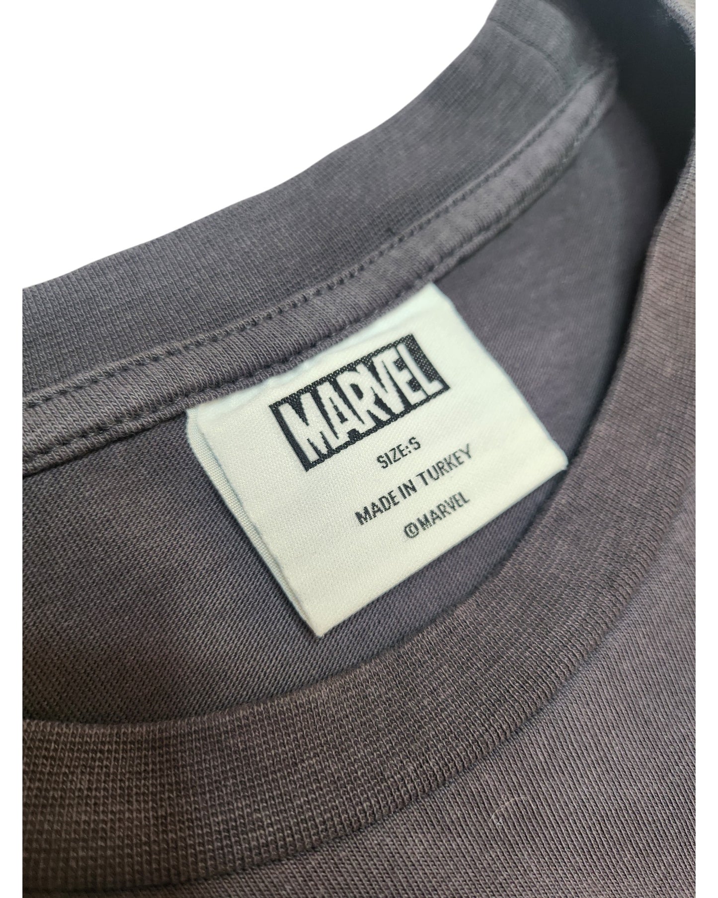 A close-up of a gray Upcycled Breastfeeding & Pumping Hulk Marvel t-shirt (size S, UK10/12) by Primark shows the white Marvel logo tag, made in Turkey, and ©Marvel.