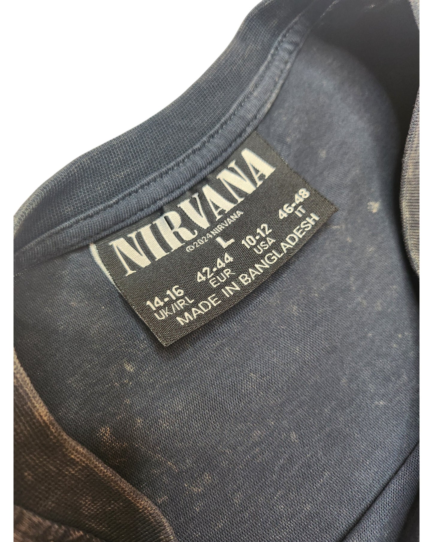 Close-up of a Primark upcycled grey/turquoise Nirvana Angel Band t-shirt (L, UK14/16), featuring a Nirvana label with size info and Made in Bangladesh text. Faded spots on the eco-friendly fabric add vintage character, ideal for nursing and pumping.
