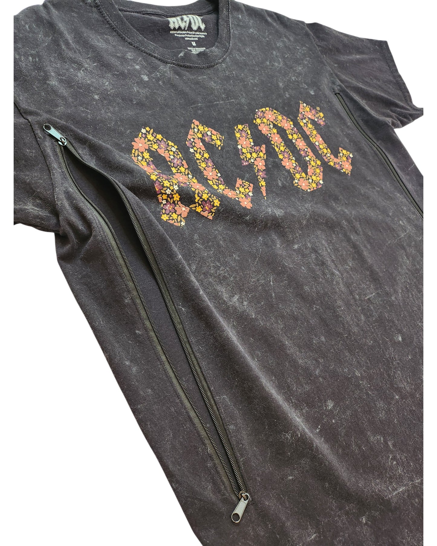 The Upcycled Breastfeeding & Pumping Floral AC/DC Band t-shirt (M) by AC/DC is a black marble-washed tee with a yellow and pink floral logo and two diagonal black zippers—ideal for nursing or pumping.