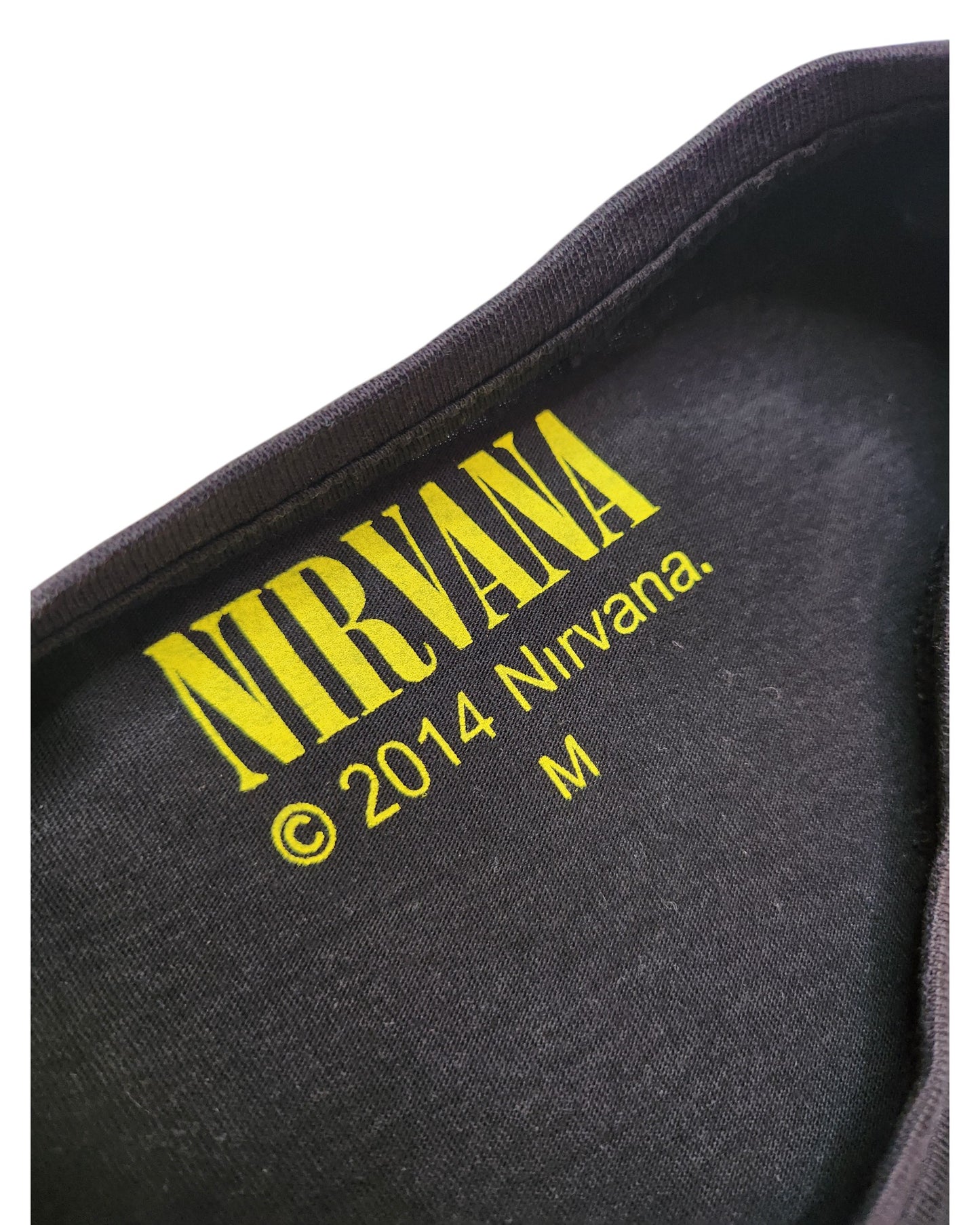 Close-up of a black Cedar Wood State t-shirt’s inner collar showing the yellow NIRVANA logo, copyright © 2014 Nirvana, and size M—a unique upcycled breastfeeding and pumping band tee for fans.