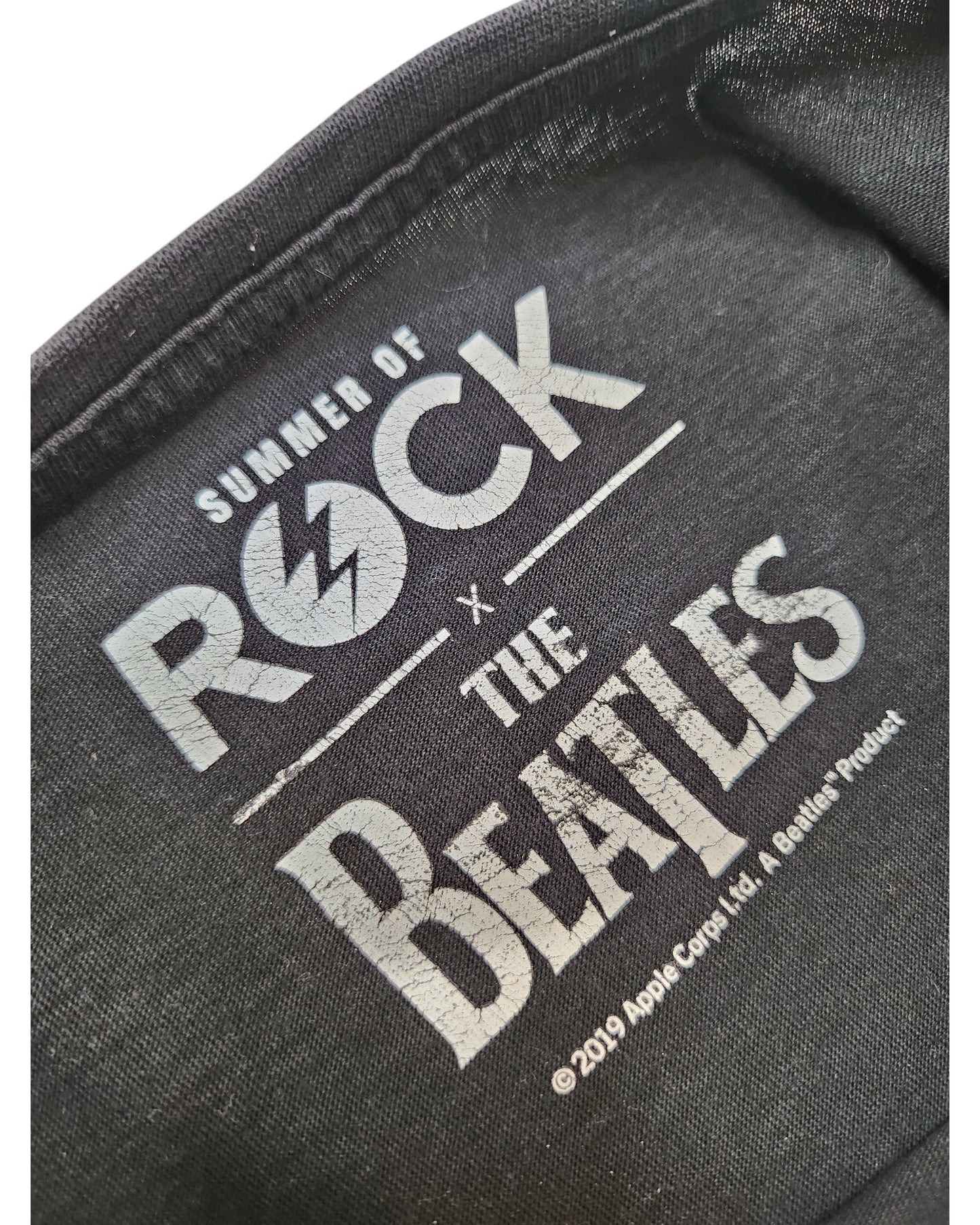 Close-up of a label on the Summer of Rock Upcycled Breastfeeding & Pumping The Beatles t-shirt UK10, featuring white text and celebrating eco-friendly fashion.