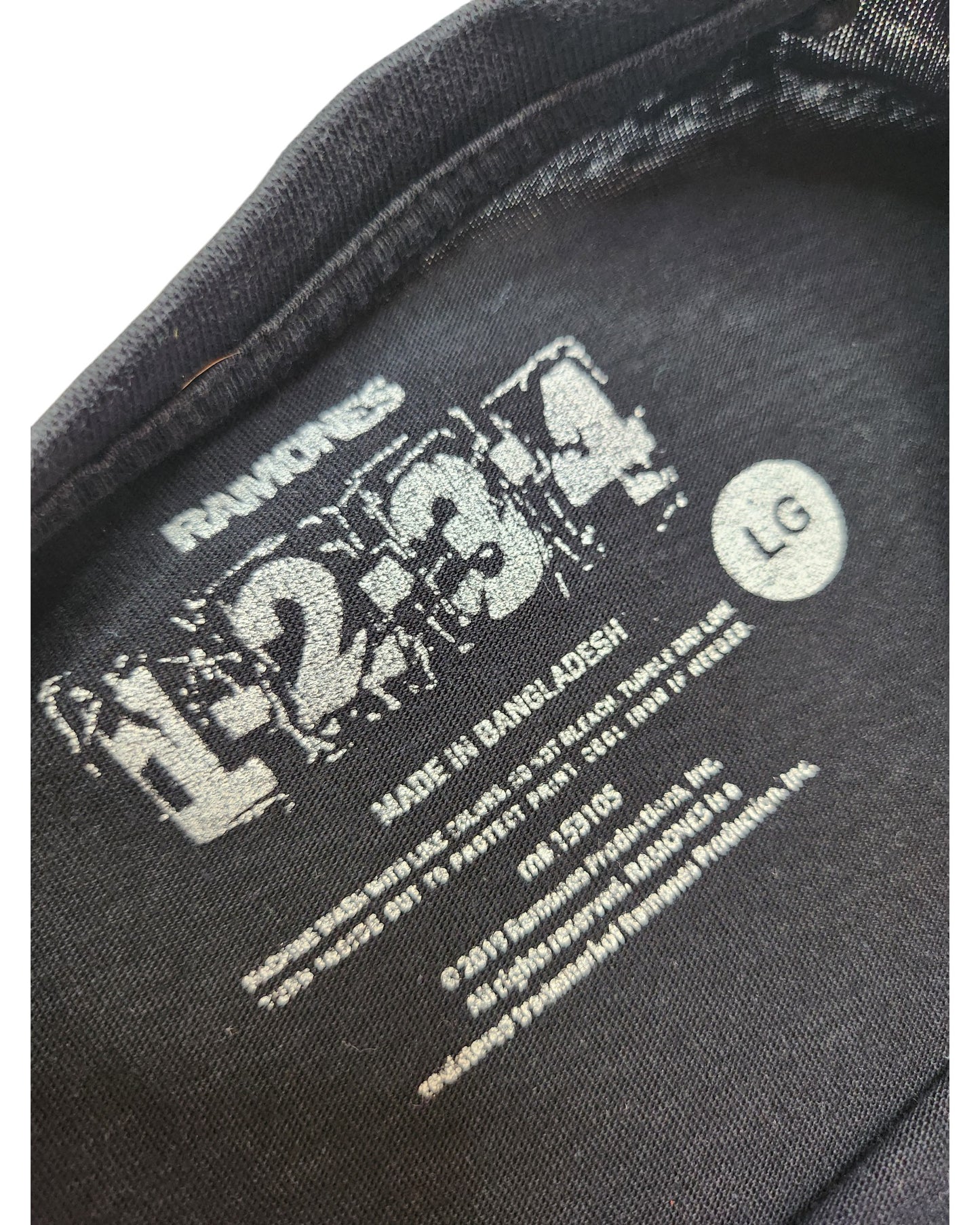 Close-up of a black Primark tag inside an upcycled breastfeeding & pumping Ramones Band t-shirt, size L, made in Bangladesh—ideal for fans seeking unique, sustainable fashion.