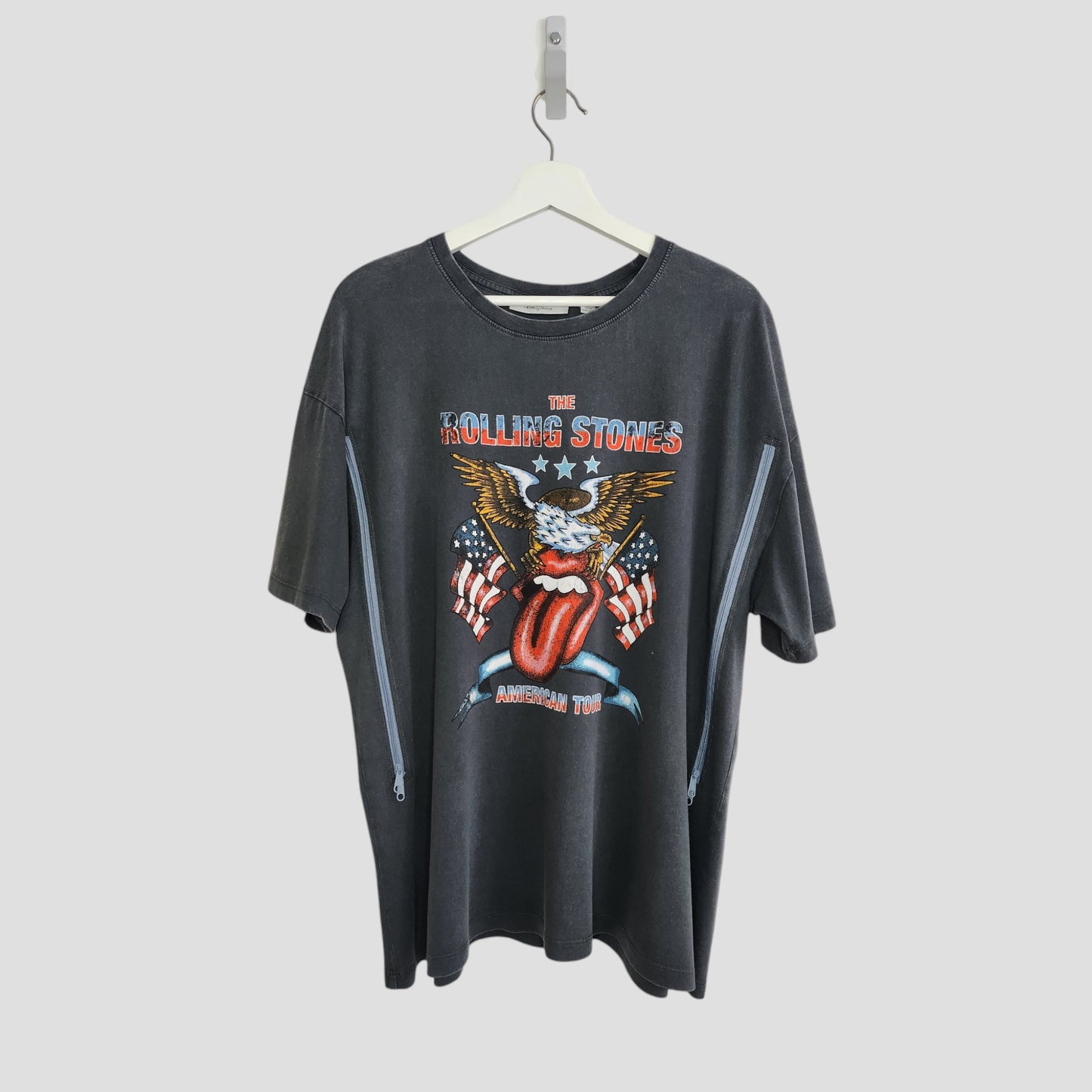 An upcycled black Rolling Stones US t-shirt (size L) by The Rolling Stones, designed for breastfeeding and pumping—features the band’s iconic graphics and “American Tour” on the front; displayed on a hanger against a white background.