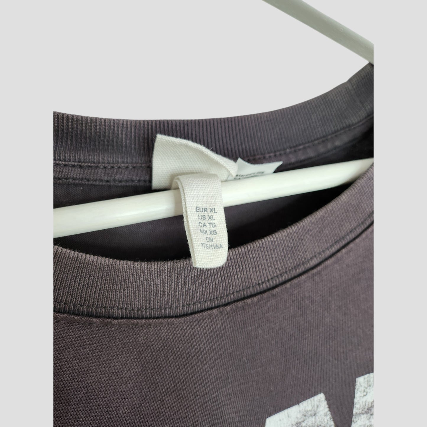 A close-up of a gray H&M Star Wars XL T-shirt on a white hanger highlights the sizing label. This upcycled breastfeeding & pumping tee is perfect for those seeking stylish preloved clothing.
