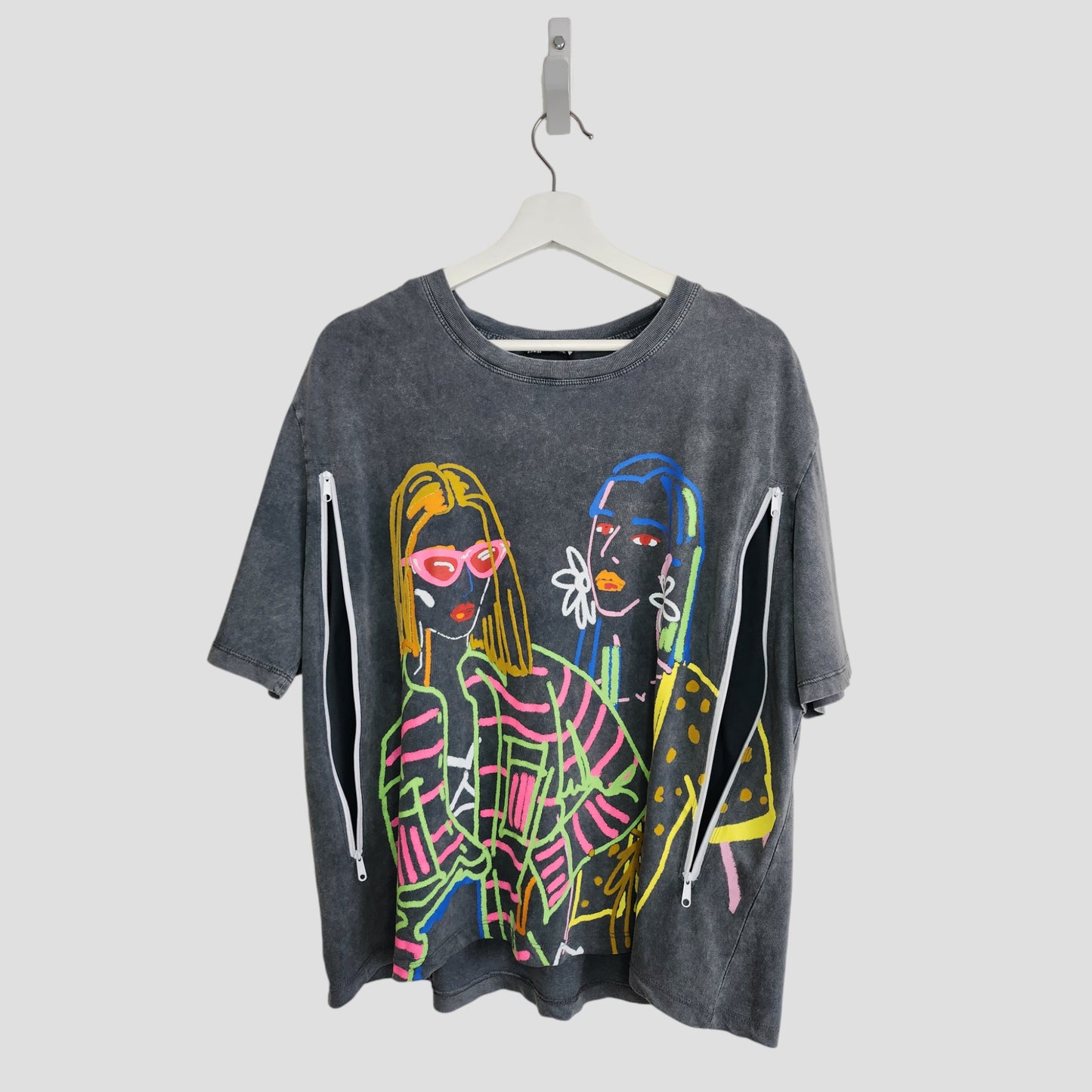 A gray ZARA Upcycled Breastfeeding & Pumping Girl Outlines t-shirt (size L) with colorful abstract illustrations of two women in accessories, celebrating preloved fashion, hangs on a white hanger.