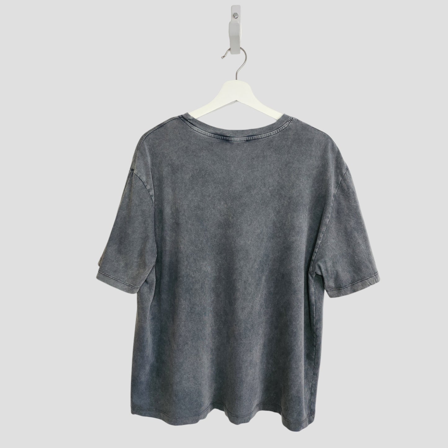 The Upcycled Breastfeeding & Pumping Grey ZARA Girl Outlines t-shirt (L) by ZARA hangs on a white hanger against a light gray background, shown from the back.