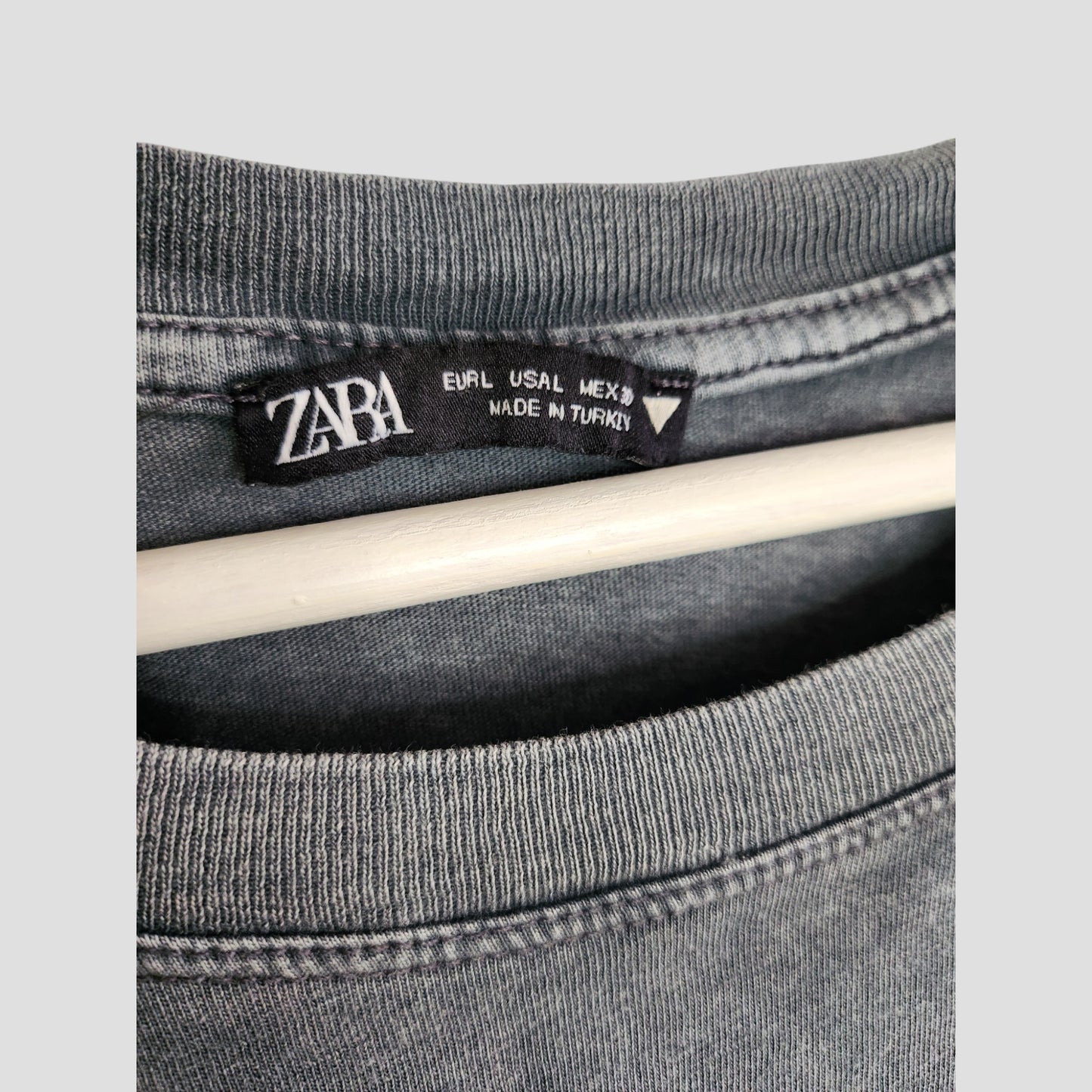 Close-up of a grey ZARA Upcycled Breastfeeding (Nursing) & Pumping Girl Outlines t-shirt in size L, showing the black ZARA label and MADE IN TURKEY, hanging on a white hanger—ideal for preloved clothing collections.