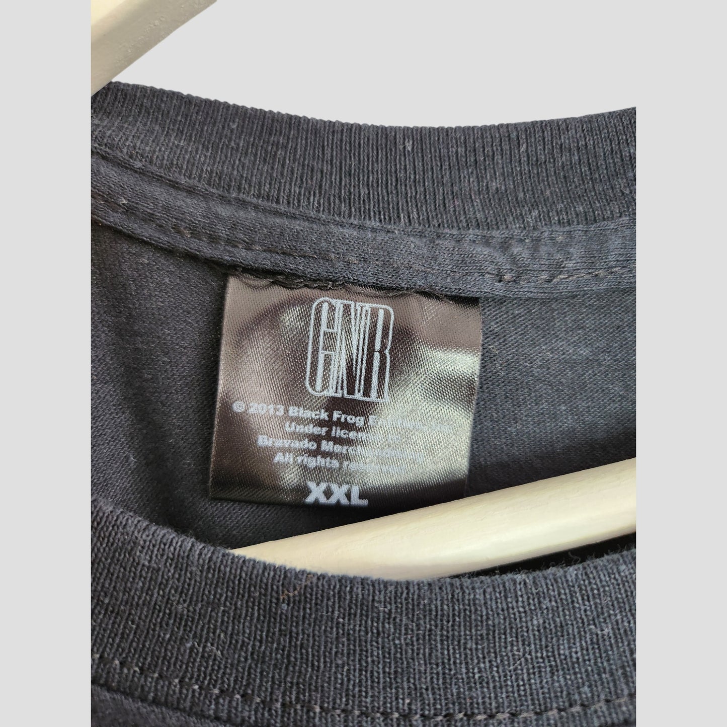 Close-up of the collar of an upcycled XXL black GNR Cross Guns n Roses breastfeeding & pumping t-shirt, showing the label with GNR logo, copyright details, Bravado Merchandise text, and size printed in white.
