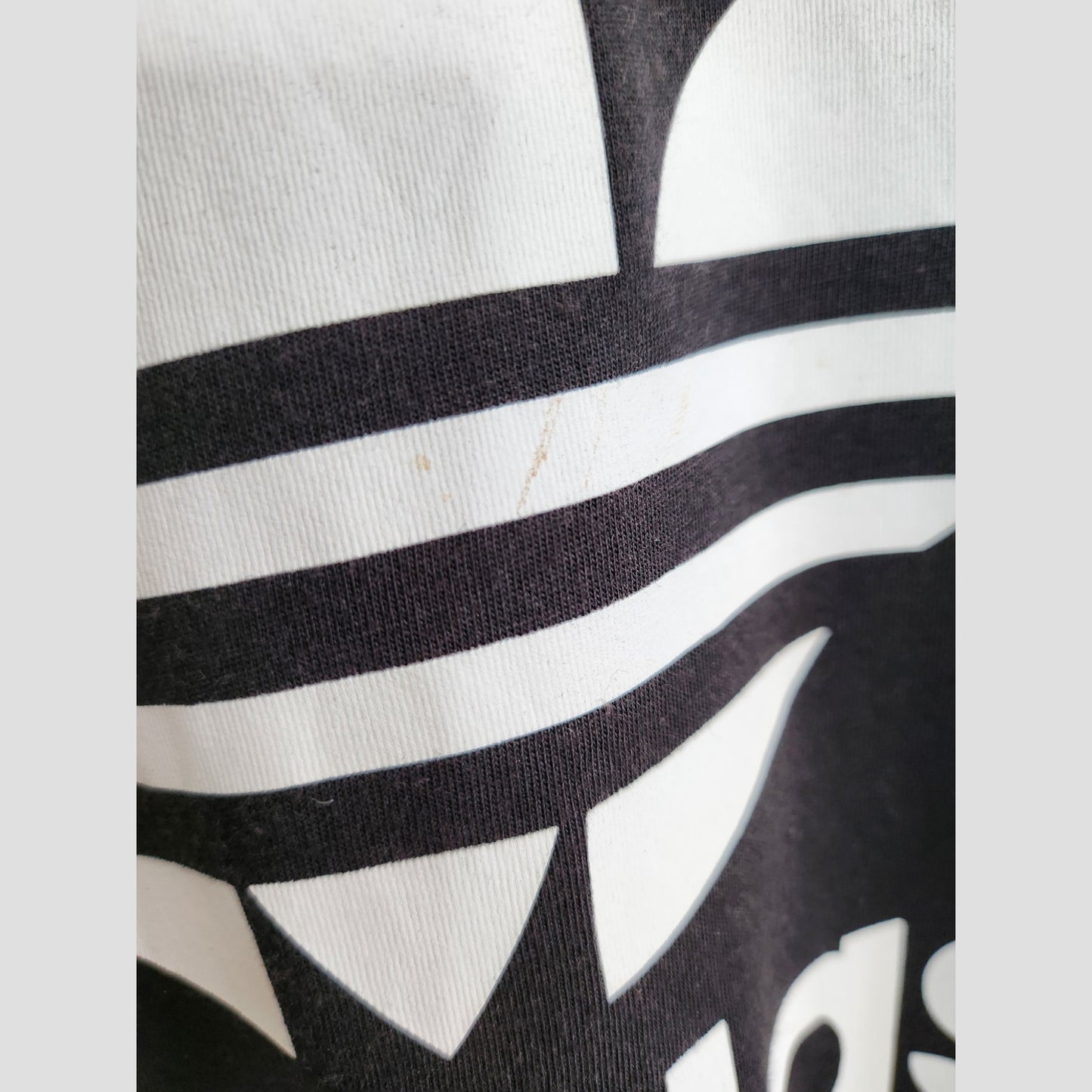 Close-up of a preloved Adidas Upcycled Breastfeeding & Pumping Black/White t-shirt (UK14) featuring a bold white graphic and faint brown stain near the center.