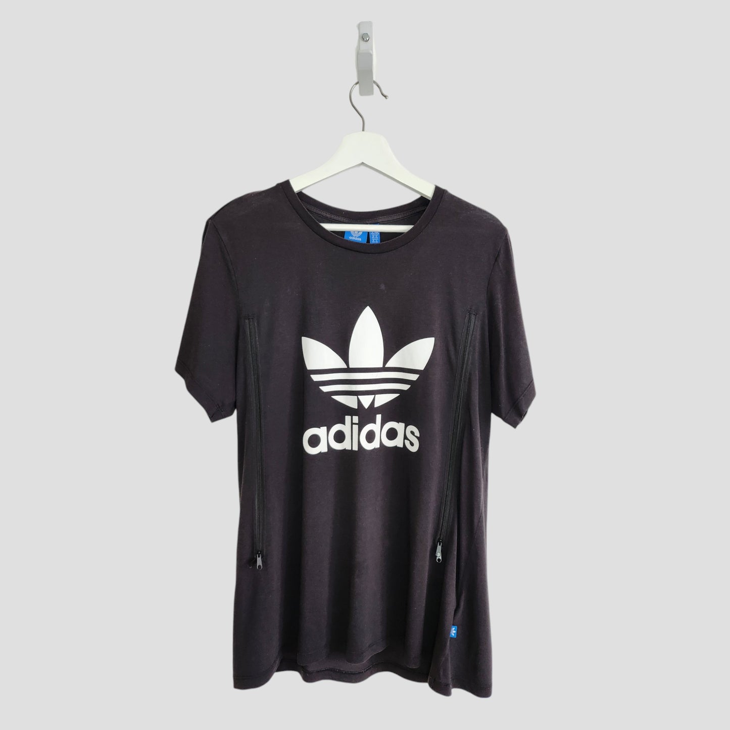 An upcycled Adidas black and white breastfeeding & pumping T-shirt (UK14) with trefoil logo and adidas text on the front, shown on a white hanger against a light gray background.