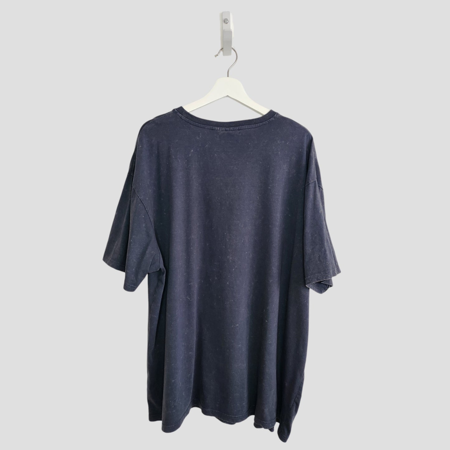 The Primark Upcycled Breastfeeding & Pumping Grey/Turquoise Nirvana Angel Band t-shirt (XL, UK18/20) made from eco-friendly materials hangs on a white hanger against a light gray background, shown from the back.