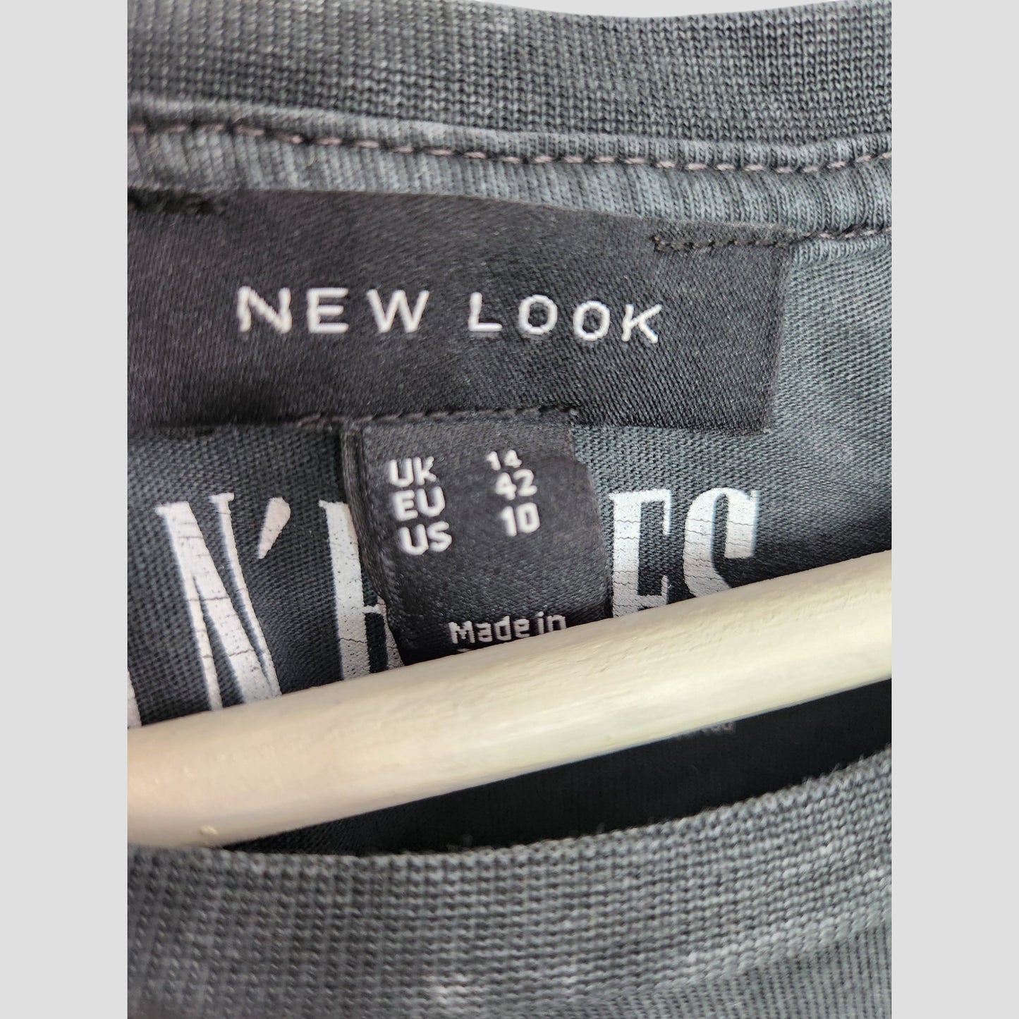 Close-up of a New Look clothing label on an upcycled breastfeeding & pumping grey Guns n Roses band t-shirt (UK14). Size tag: UK 14, EU 42, US 10. Wooden hanger visible—ideal for displaying preloved fashion.