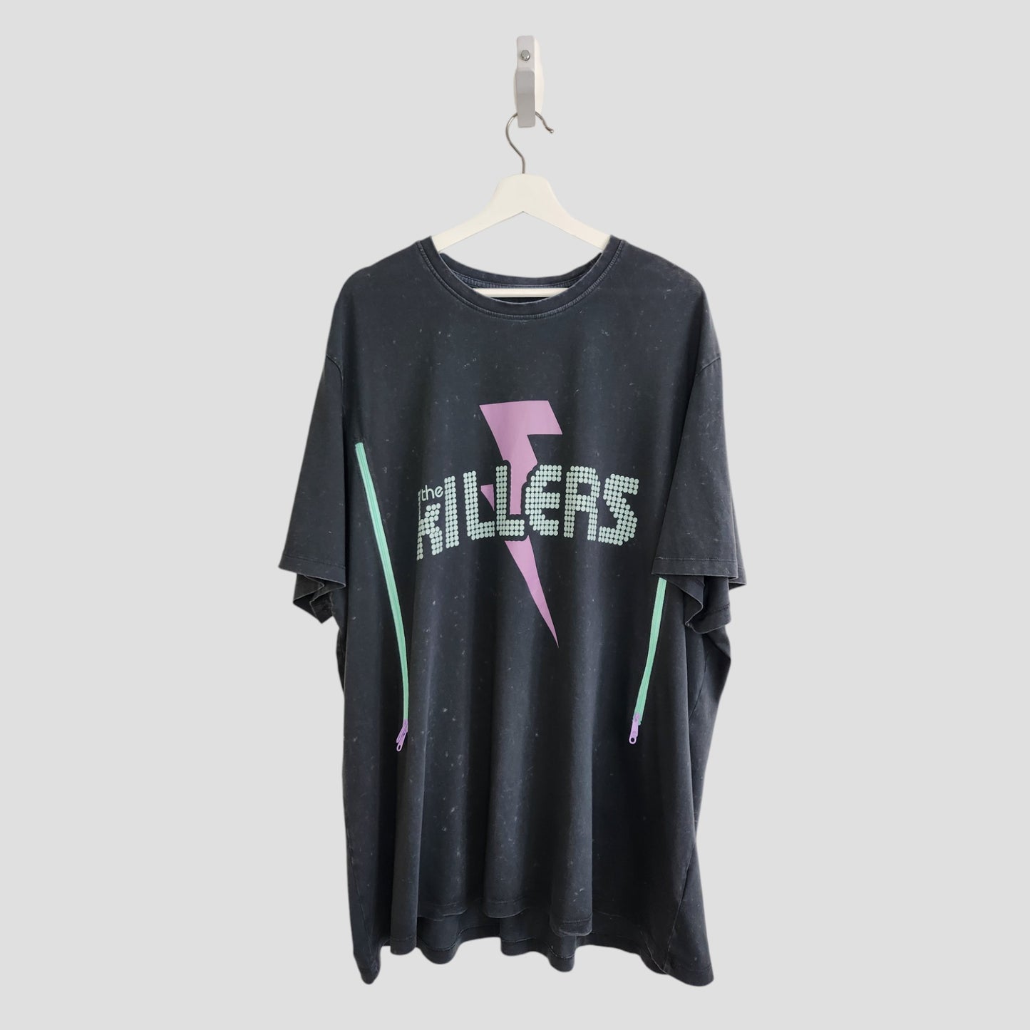 An upcycled 3XL black The Killers band T-shirt for breastfeeding and pumping, featuring white dotted lettering and a pink lightning bolt—a unique find for preloved fashion fans.