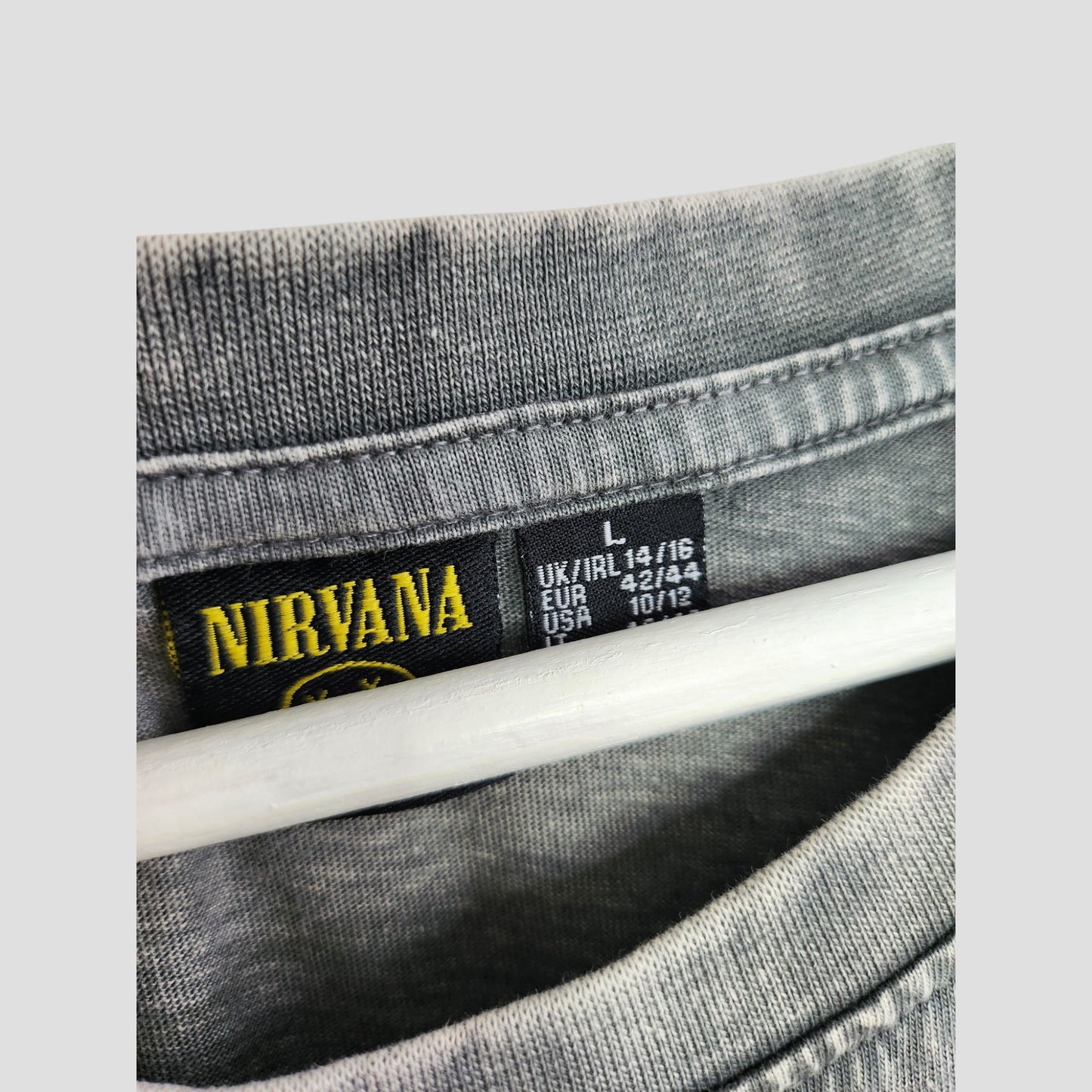 Close-up of the collar on a Primark Upcycled Breastfeeding & Pumping Grey/Pink Nirvana Angel t-shirt dress, size L (UK 14/16), EU 42/44, USA 10/12—ideal for fans seeking stylish nursing wear. Hanger is partly visible below the collar.