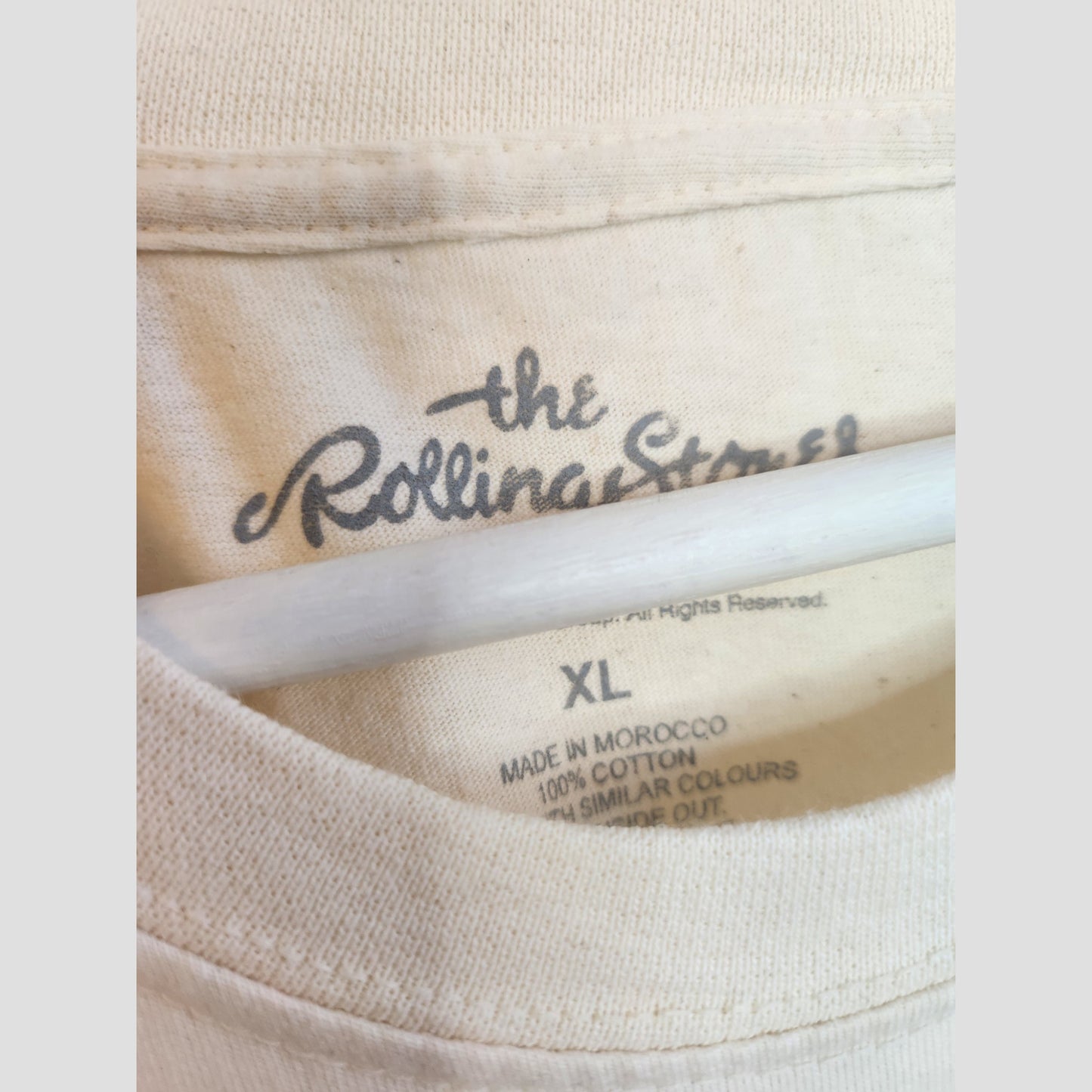 A close-up of the XL label on The Rolling Stones Upcycled Breastfeeding & Pumping Cream/Pink Band T-shirt (100272), made in Morocco from 100% cotton, featuring care instructions for eco-friendly washing.