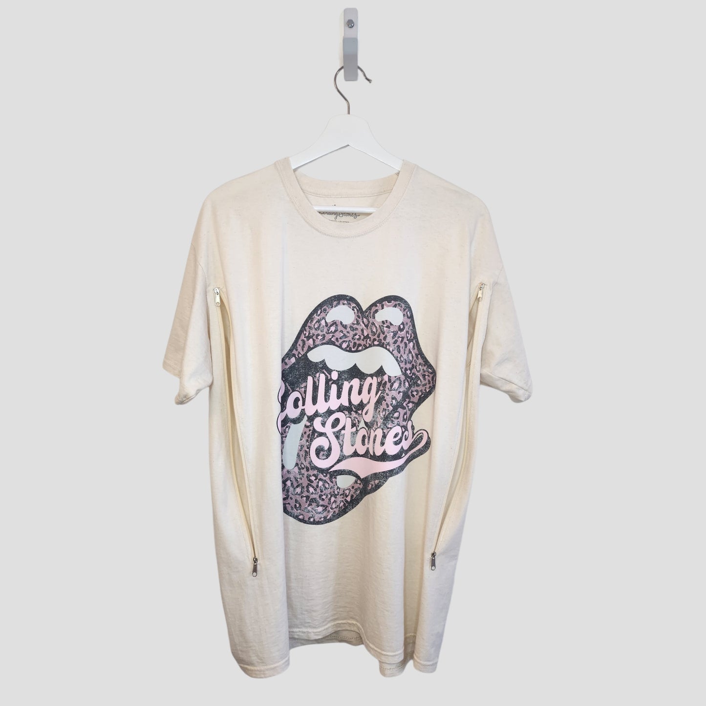 The Rolling Stones Upcycled Breastfeeding & Pumping T-shirt (XL) features a cream/pink band graphic with lips, tongue, leopard print, and “Rolling Stone” text. Includes vertical zippers on both sleeves for nursing or pumping ease.