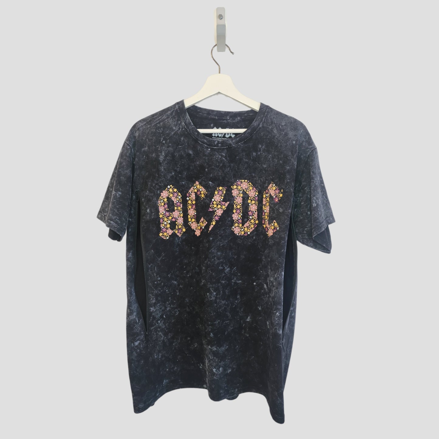 The AC/DC Upcycled Breastfeeding & Pumping Black Floral Band T-shirt (L, 100202) hangs on a white hanger against a plain light background.