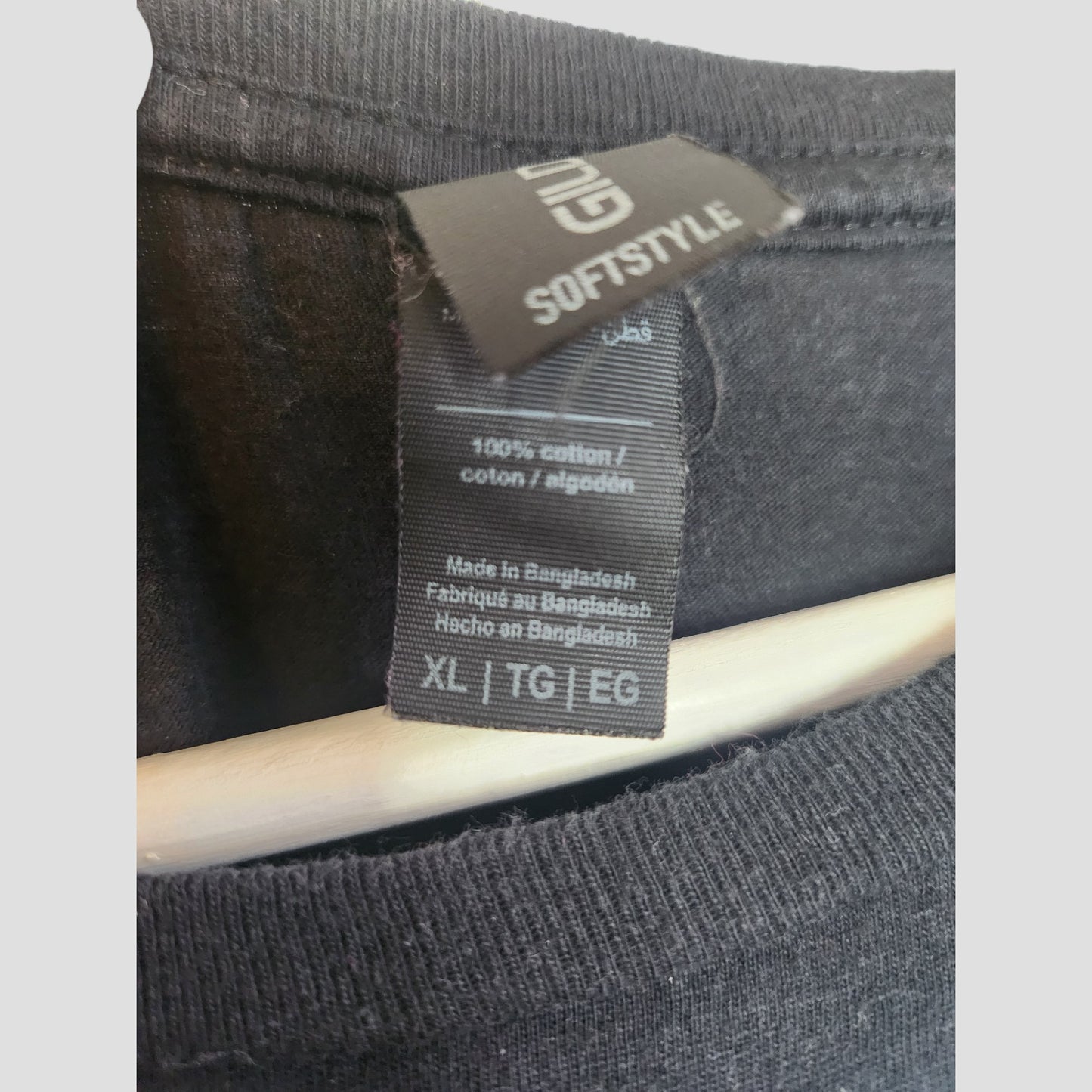 A close-up shows the Gildan label on an upcycled Black Skull Green Day Band breastfeeding & pumping T-shirt, size XL (100187), draped over a wooden hanger—perfect for eco-conscious nursing clothes fans.