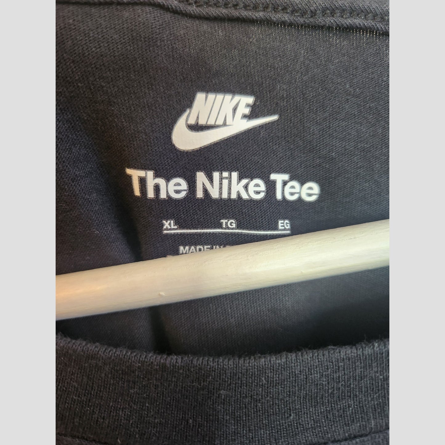 Close-up of a Nike XL upcycled breastfeeding & pumping t-shirt label, featuring the white Nike tick and size info—ideal for eco-conscious fashion lovers.