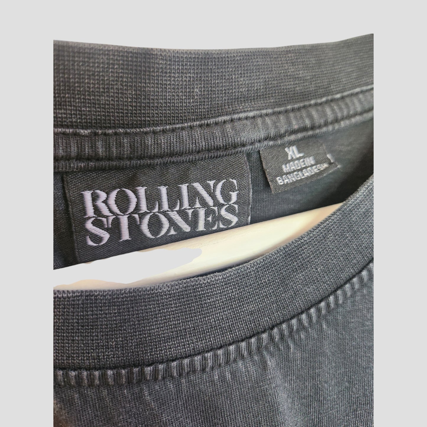 Close-up of a Primark Upcycled Breastfeeding & Pumping Black Voodoo The Rolling Stones Band T-shirt in XL, made in Bangladesh. The label and collar detail highlight the quality stitching and fabric texture.