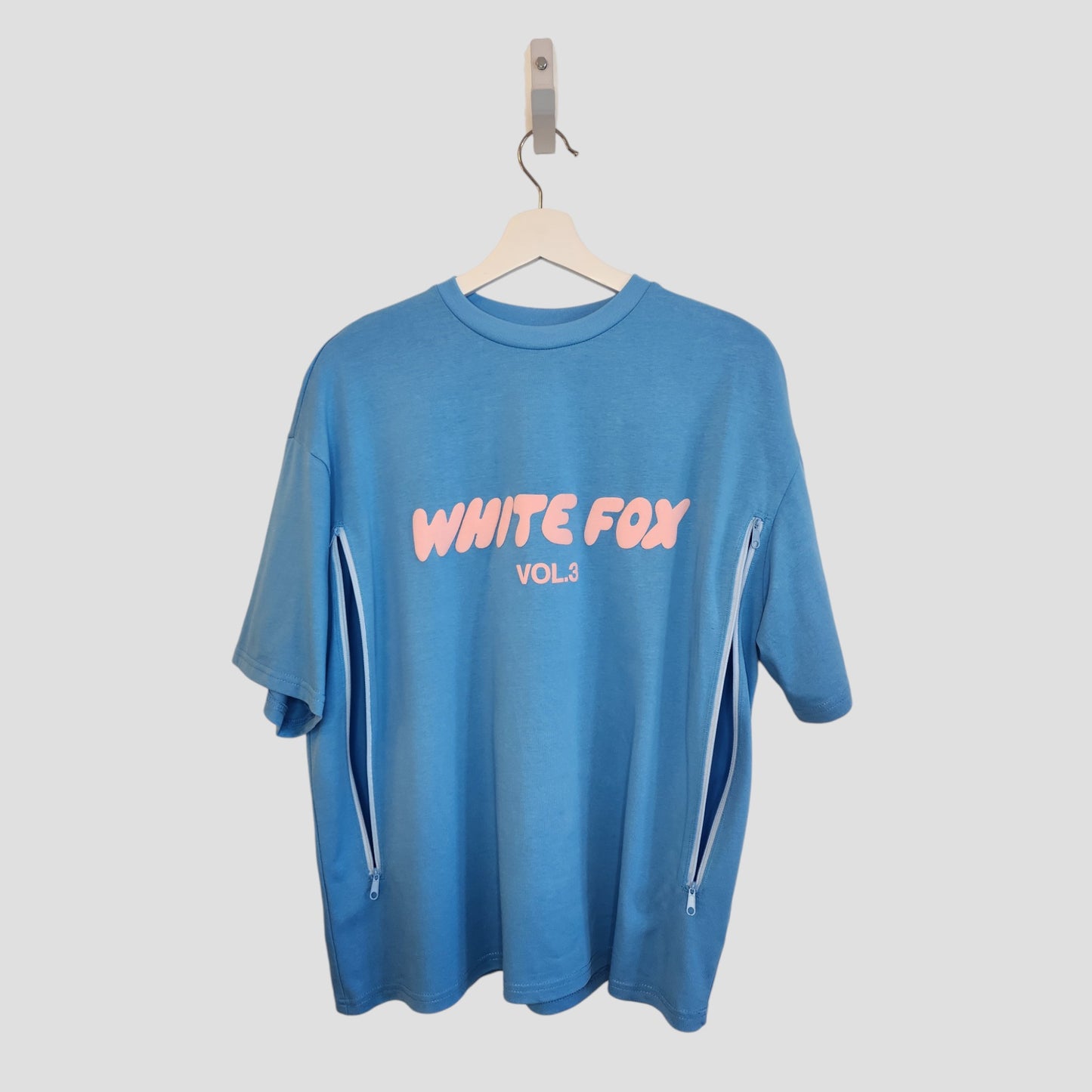 The Upcycled Breastfeeding (Nursing) & Pumping Blue White Fox t-shirt M (100265) features pink WHITE FOX VOL.3 text on the front and white vertical side zippers—ideal for nursing or pumping. Brand: Unknown.