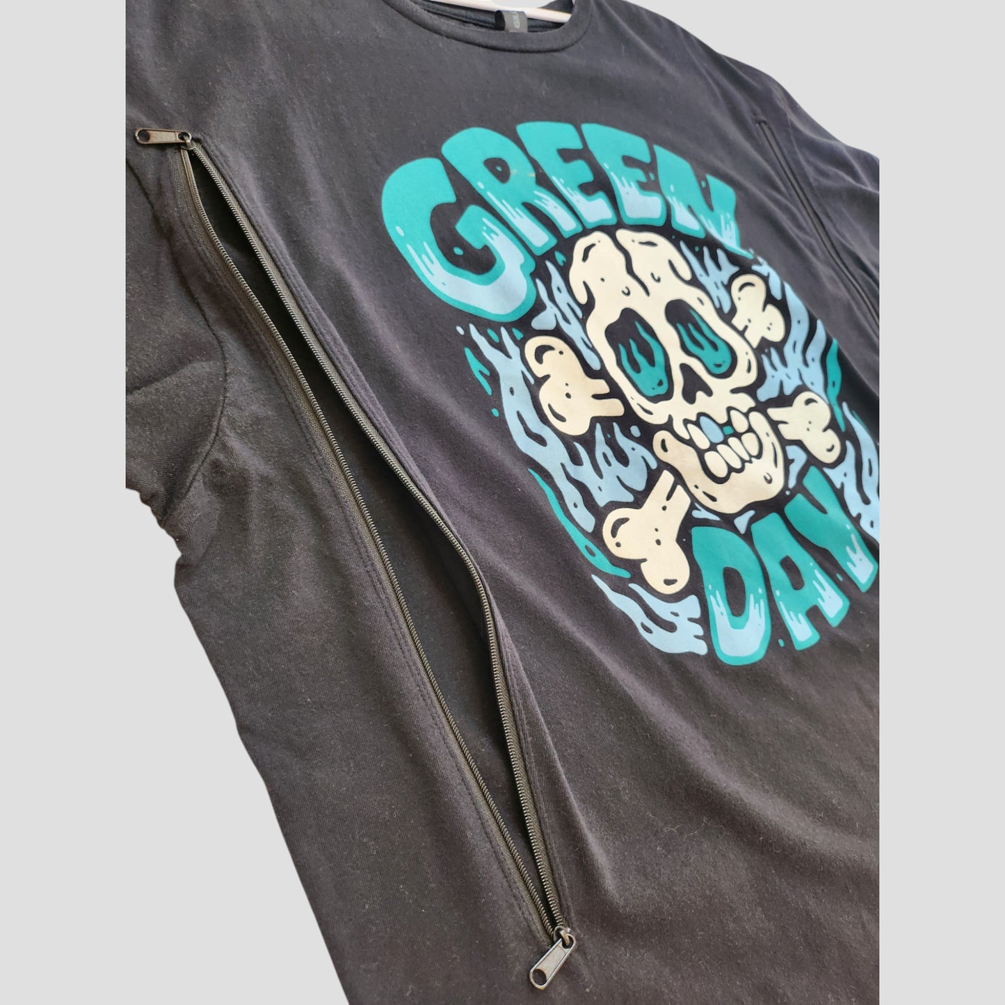 Gildan Upcycled Breastfeeding & Pumping Black Skull Green Day Band T-shirt (XL, 100187) features a blue and white skull design with a long zipper for nursing access. Preloved item shown laid flat on a light background.