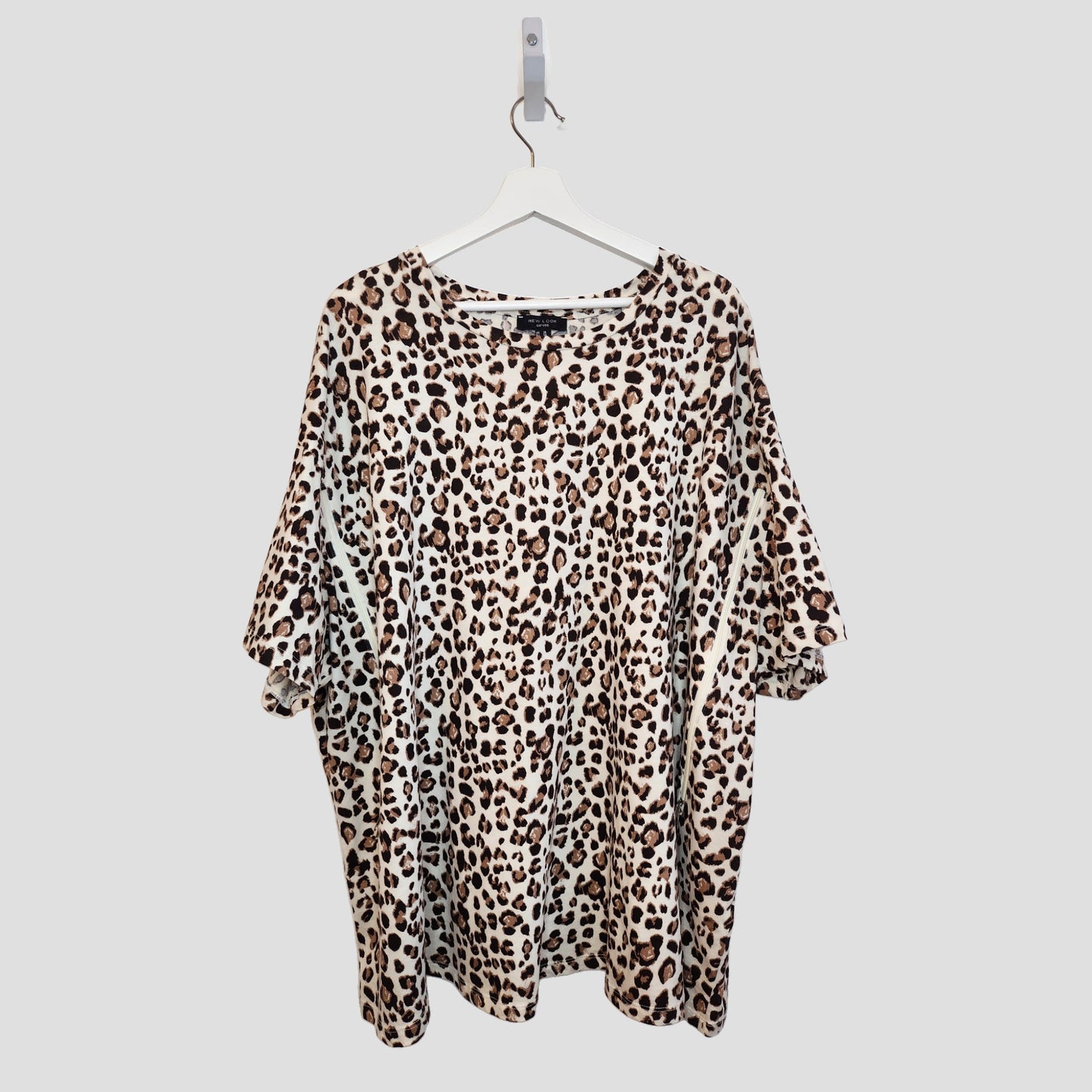The New Look Upcycled Breastfeeding & Pumping Cream Leopard t-shirt UK26 (100290) features a loose fit and short sleeves, crafted from preloved clothing in a brown and black leopard print, shown on a white hanger against a light gray background.