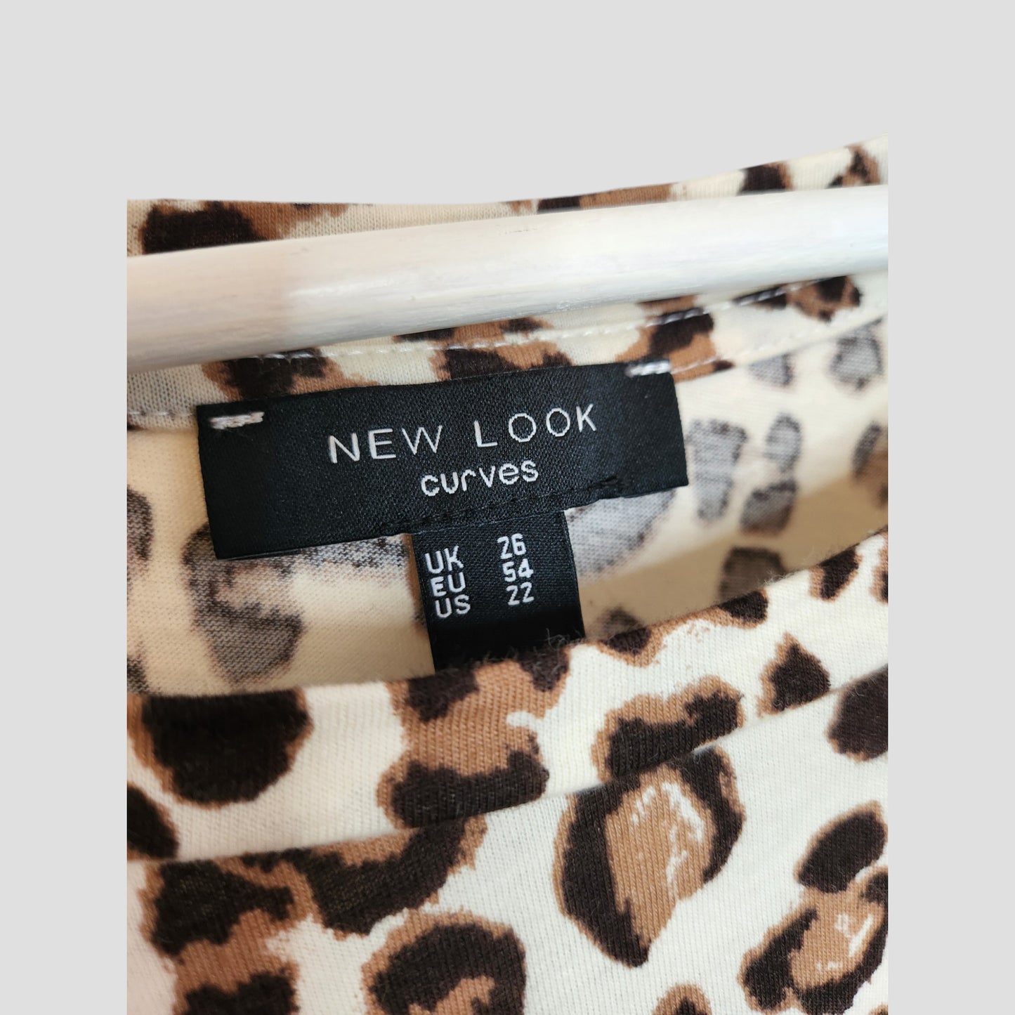 Close-up of the clothing label on a cream leopard print Upcycled Breastfeeding & Pumping t-shirt by New Look, size UK 26 (EU 54, US 22)—a stylish preloved find for nursing moms seeking comfort and fashion.