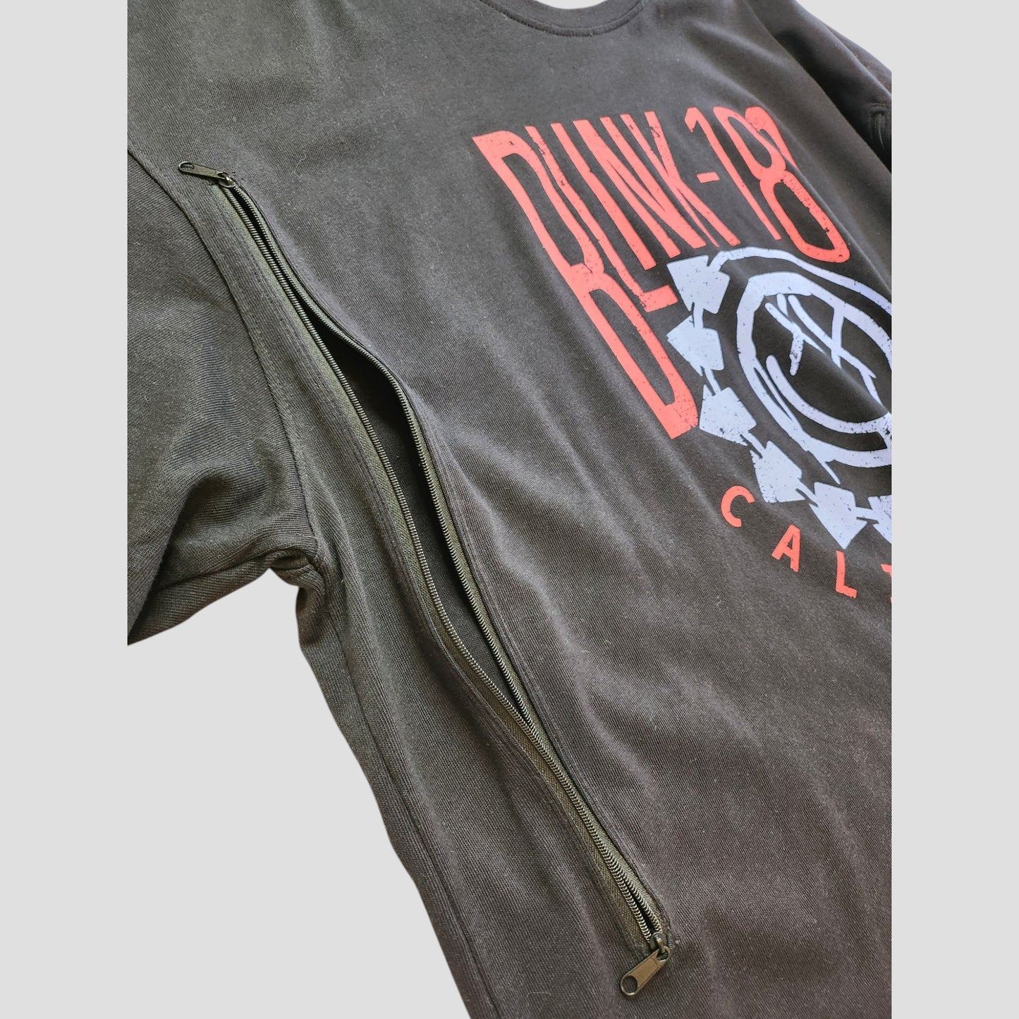 The boohoo Upcycled Breastfeeding & Pumping Black Blink-182 t-shirt UK16 (100294) features a red and white graphic with a discreet diagonal side zipper, making it ideal for nursing or pumping.
