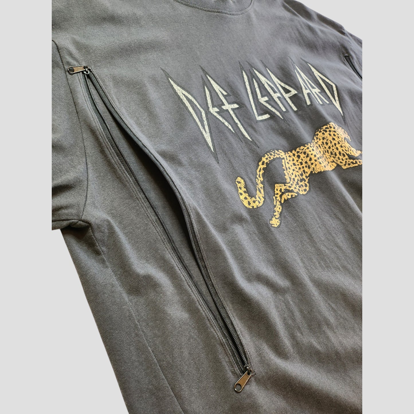 The H&M Upcycled Breastfeeding & Pumping Def Leppard T-shirt XL (100257) features a gray design with a leopard graphic, dual vertical black zippers for nursing access—an eco-friendly, stylish choice for moms.