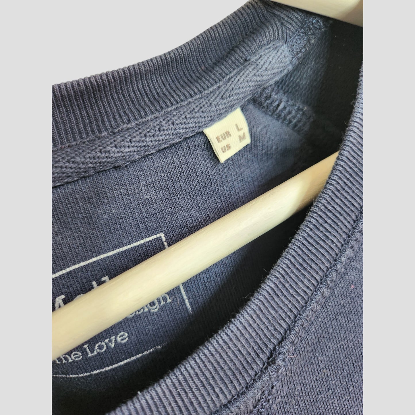 Close-up of Selfish Mother’s Upcycled Breastfeeding & Pumping Navy Blue Winging It Sweatshirt (size EUR L, US M) on a hanger—eco-friendly preloved fashion for your sustainable wardrobe.