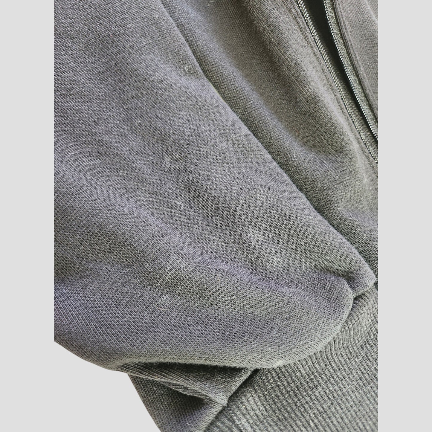 Close-up of the Upcycled Breastfeeding & Pumping Black/Leopard The Rolling Stones Band Sweatshirt (UK14) showing worn texture, pilling, and lint balls on the sleeve, with a visible zipper and ribbed cuff.