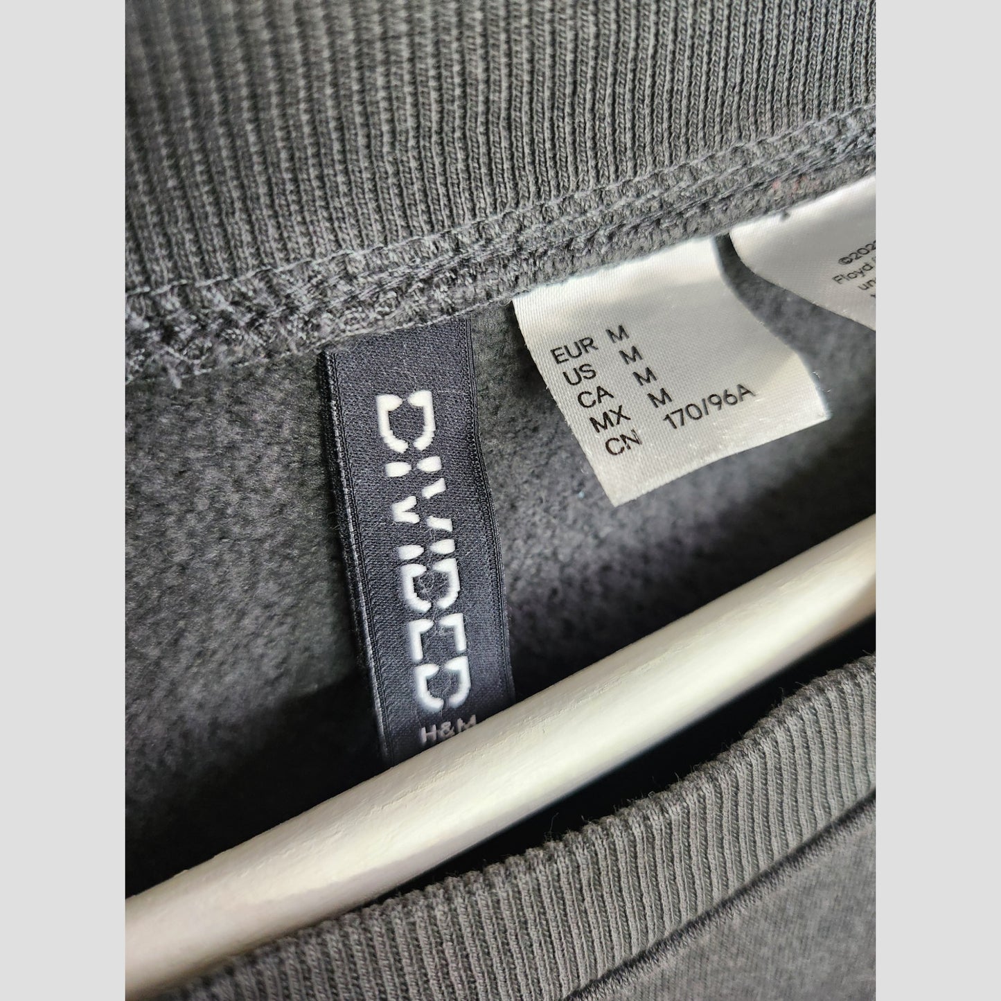 Close-up of a gray Upcycled Breastfeeding & Pumping Pink Floyd Oversized Band Sweatshirt (M, UK12/14) by Primark, on hanger—an affordable eco choice for stylish and sustainable nursing wear.