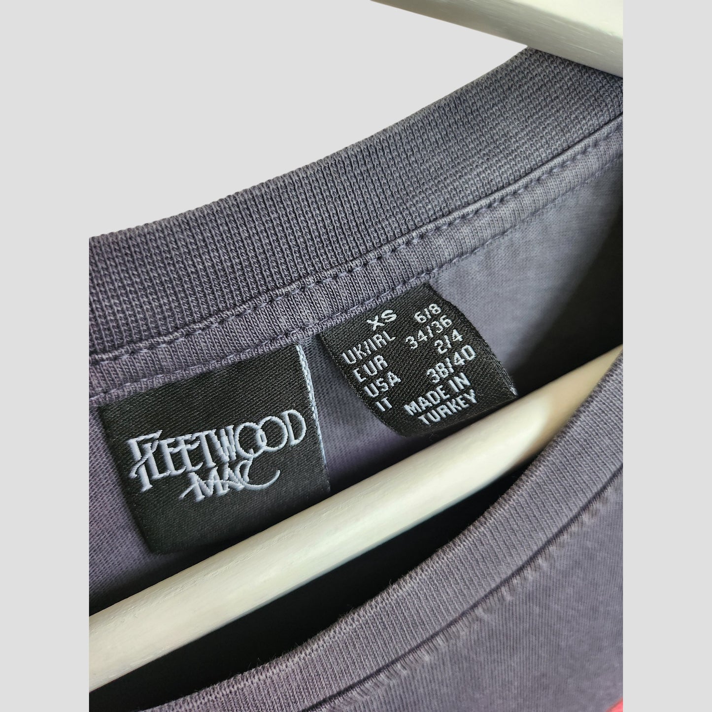 Close-up of a grey Primark oversized t-shirt (XS, UK8/10) featuring a black Fleetwood Mac label. Upcycled for breastfeeding and pumping, with floral band design—ideal for eco-conscious maternity or preloved nursing wear.