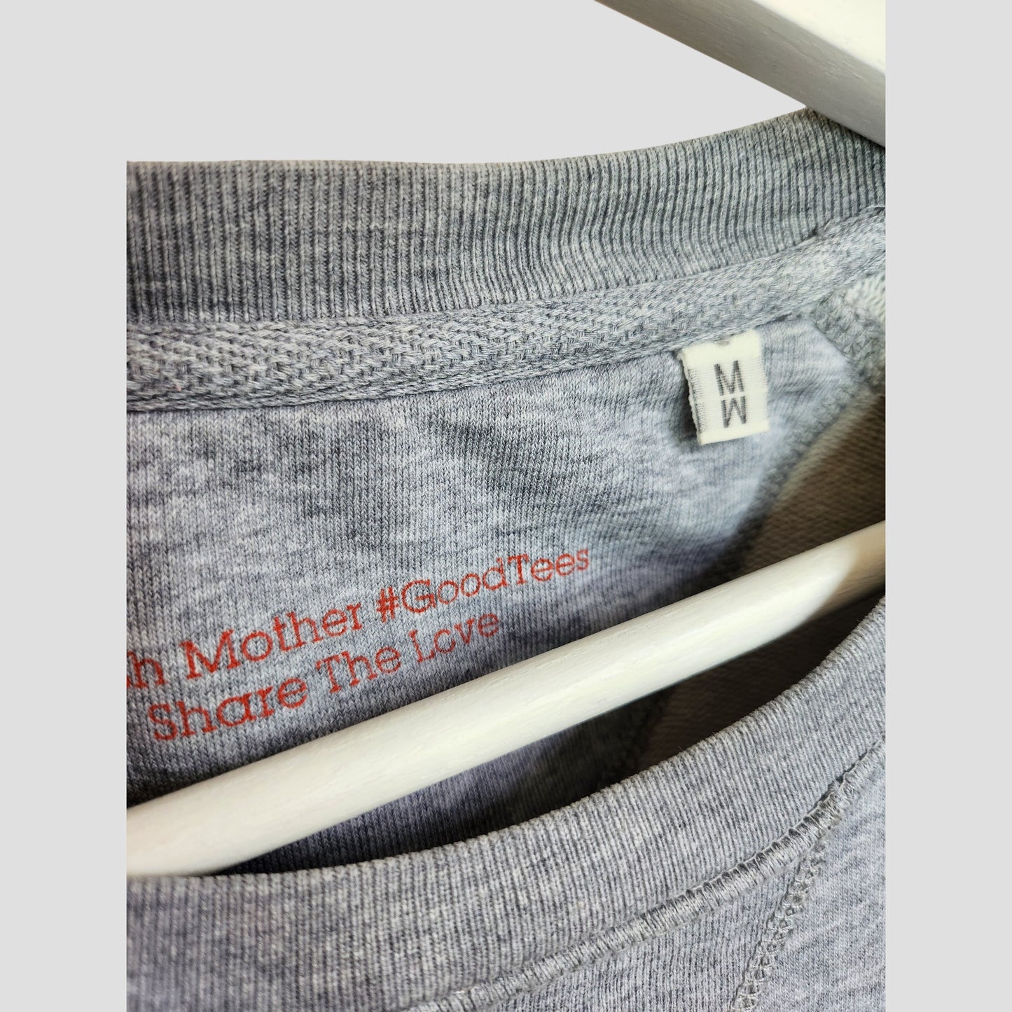 Close-up of the Selfish Mother Upcycled Breastfeeding & Pumping Grey/Red SUPER WOMAN Sweatshirt (M). White size tag with M/W is visible, and red #GoodTees and Share The Love text—ideal for preloved nursing wear seekers.