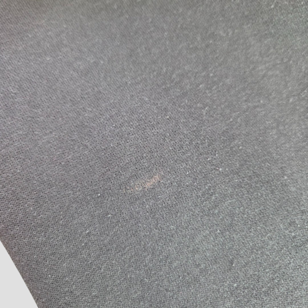 A close-up of the Primark Upcycled Breastfeeding & Pumping Grey Pink Floyd Band Sweatshirt XL shows a small, faint light brown stain near the center on the dark gray fabric, which has a uniform and smooth texture.