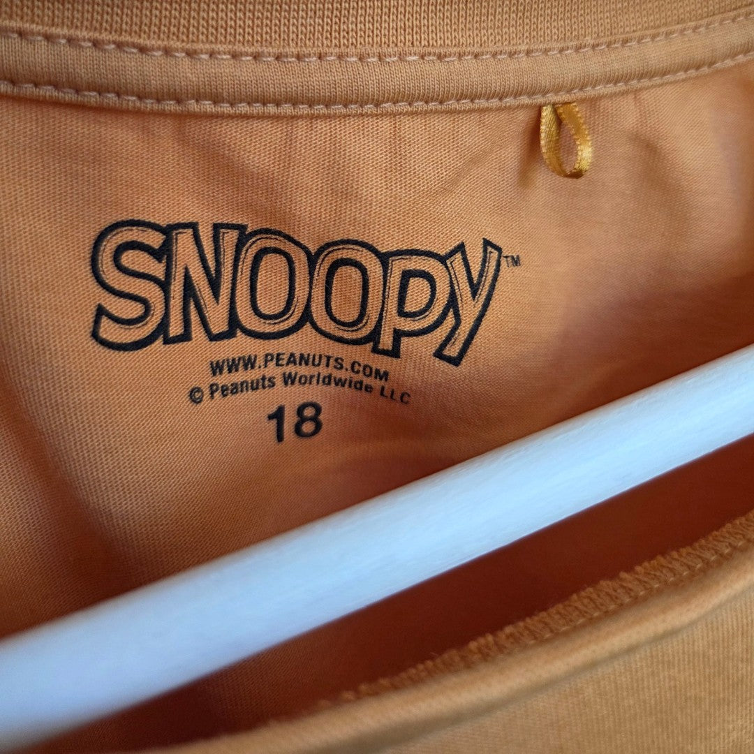 Close-up of the inside collar of the George Upcycled Breastfeeding & Pumping Orange Snoopy Flower t-shirt (UK18), showing the SNOOPY label, www.PEANUTS.com, © Peanuts Worldwide LLC, a yellow hanging loop, and white hanger.