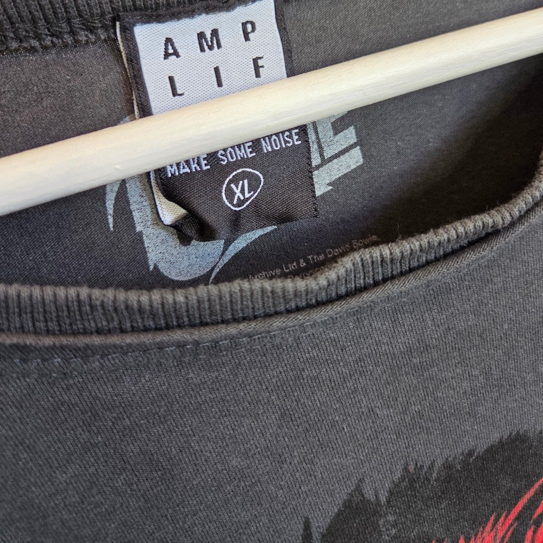 Close-up of an Amplified Upcycled Breastfeeding & Pumping Grey/Red Bowie Band t-shirt XL (100484) on a hanger, showing neck details and tags. Faint printed text and part of a graphic are visible on this affordable nursing top.