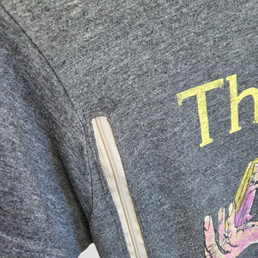 Close-up of the Truffle Shuffle Upcycled Breastfeeding & Pumping The BFG T-shirt (L), featuring gray heather fabric, a vertical white zipper on the sleeve seam, a partially visible yellow print, and a colorful graphic at the lower right.