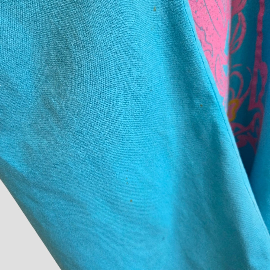 Close-up of a Primark Upcycled Breastfeeding & Pumping Turquoise/Pink Girl t-shirt (L, UK14/16), featuring light blue fabric with a partial pink and yellow print on the right edge, set against a light gray background.