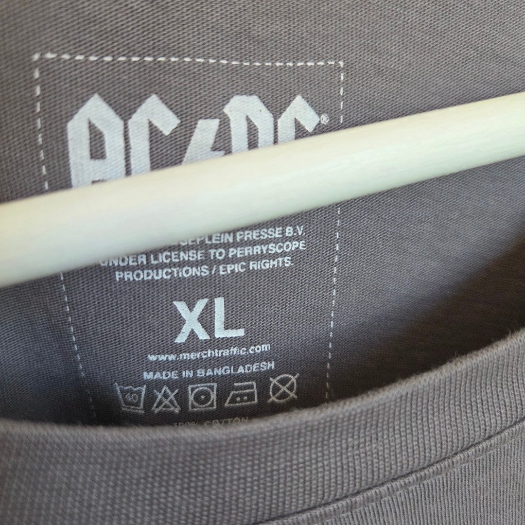 Close-up of an official AC/DC Upcycled Breastfeeding & Pumping Grey Leopard band t-shirt in XL, showing the inside label with size, care details, and origin (Bangladesh), licensed by Epic Rights. Eco-friendly; hanger included.