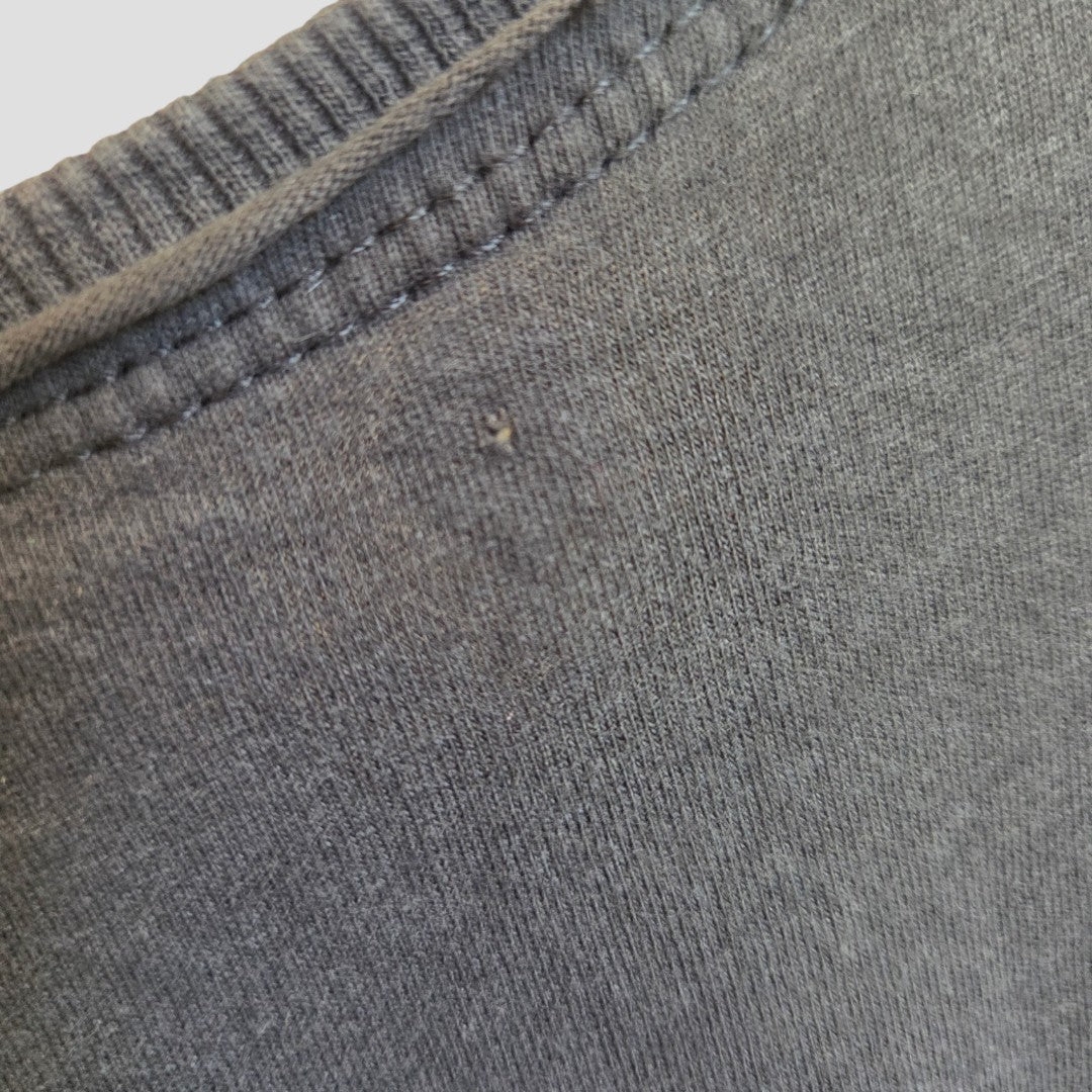 Close-up of the gray fabric of the Amplified Upcycled Breastfeeding (Nursing) & Pumping Grey Red Hot Chilli Peppers Band t-shirt, size XL (100563), showing part of the collar seam and a small hole or defect near the stitching.