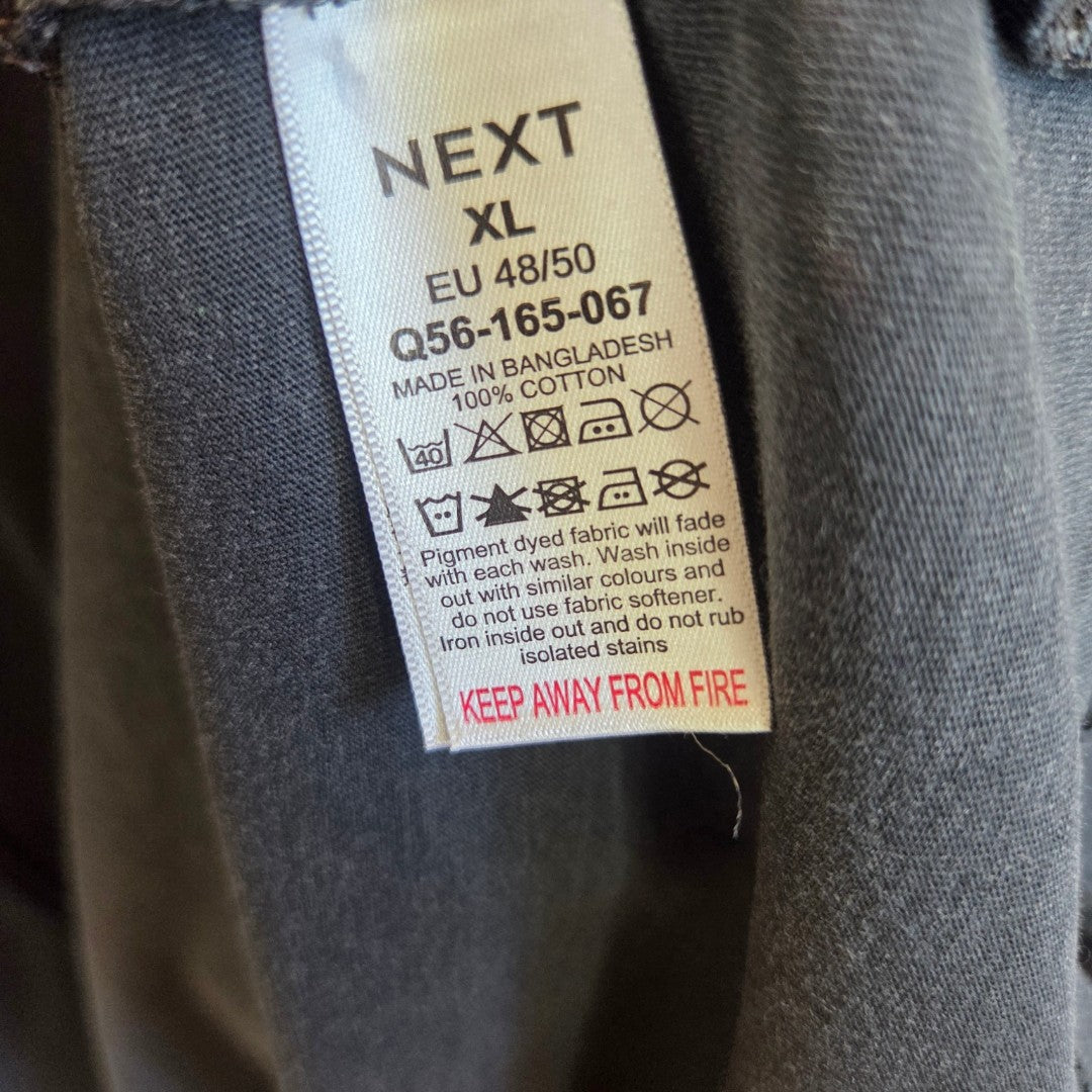 A clothing label for the Upcycled Breastfeeding (Nursing) & Pumping Grey Floral The Rolling Stones Band t-shirt XL (100557) by Next, displaying size XL (EU 48/50), made from 100% cotton, with care symbols and washing instructions—perfect for those looking for an eco-friendly nursing clothing alternative—and featuring a "KEEP AWAY FROM FIRE" warning in red at the bottom.