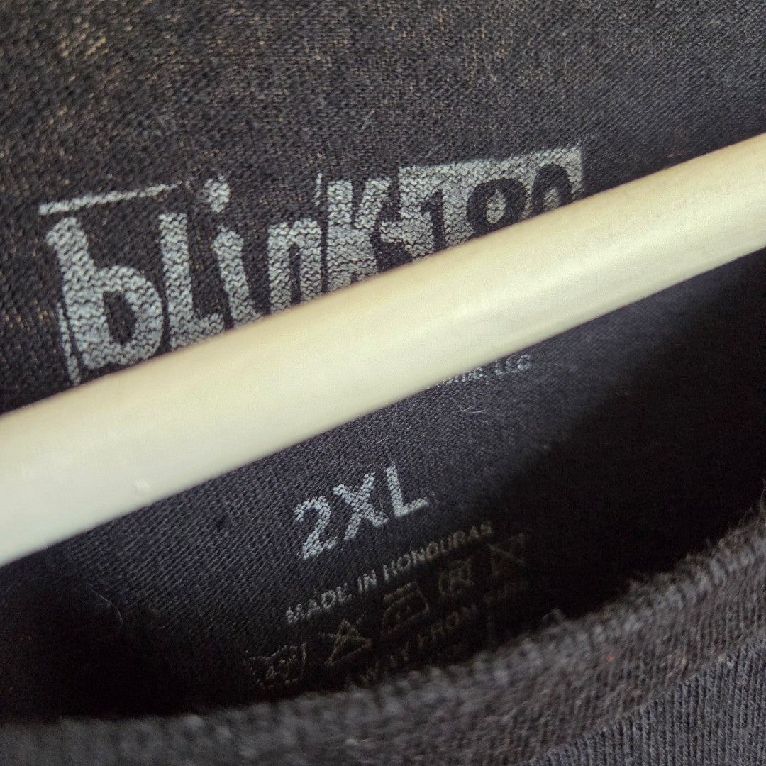 A close-up of the tag on a Blink-182 Upcycled Breastfeeding (Nursing) & Pumping Black Colourful Smile Band t-shirt in XXL, showing that it is made in Honduras from 100% cotton, with part of a white hanger visible above the label.