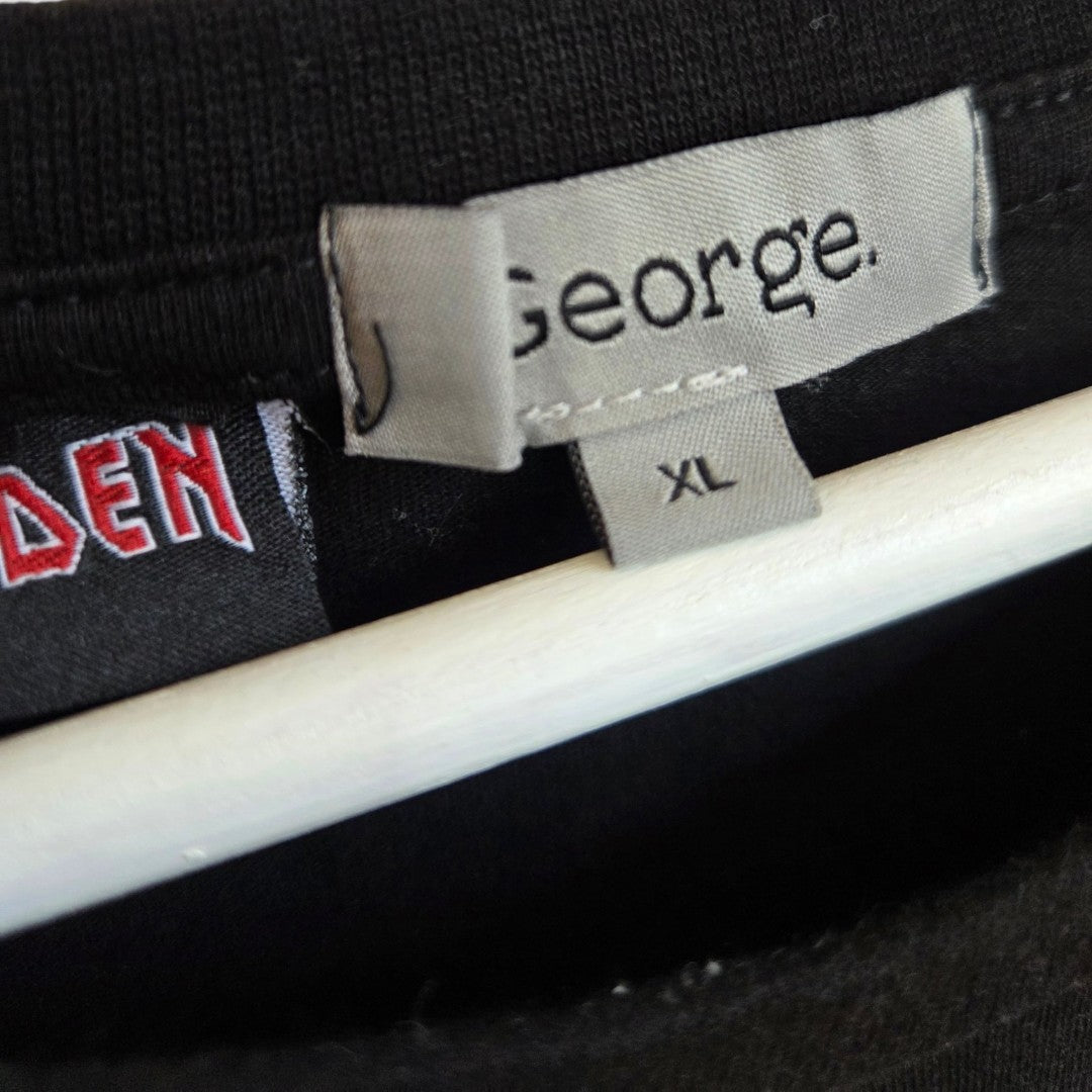 Close-up of a shirt collar displaying a George brand tag labeled XL and part of another tag with red letters, both on an Upcycled Breastfeeding (Nursing) & Pumping Iron Maiden Christmas t-shirt by George in black, hanging on a white hanger—an excellent choice for those seeking comfortable and eco-friendly nursing clothing.