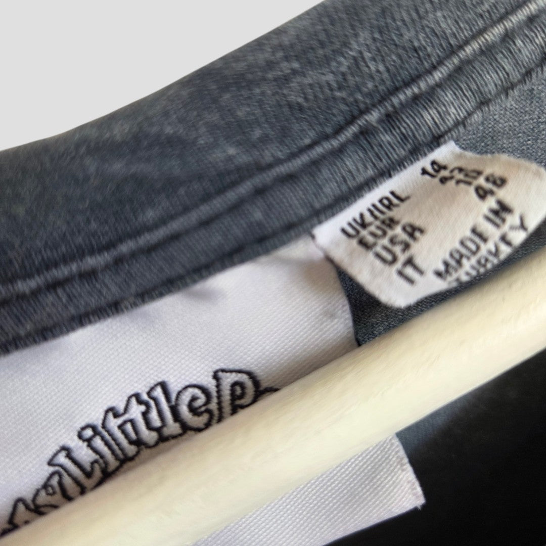 Close-up of a clothing tag on the Primark Upcycled Breastfeeding (Nursing) & Pumping Grey My Little Pony t-shirt UK14 (100600), showing size details for the UK, EU, and USA, with “IT MADE IN TURKEY” printed beneath. The edge of a hanger and part of the shirt collar are also visible—a subtle detail that reflects our dedication to providing practical and stylish upcycled nursing apparel for breastfeeding mothers.