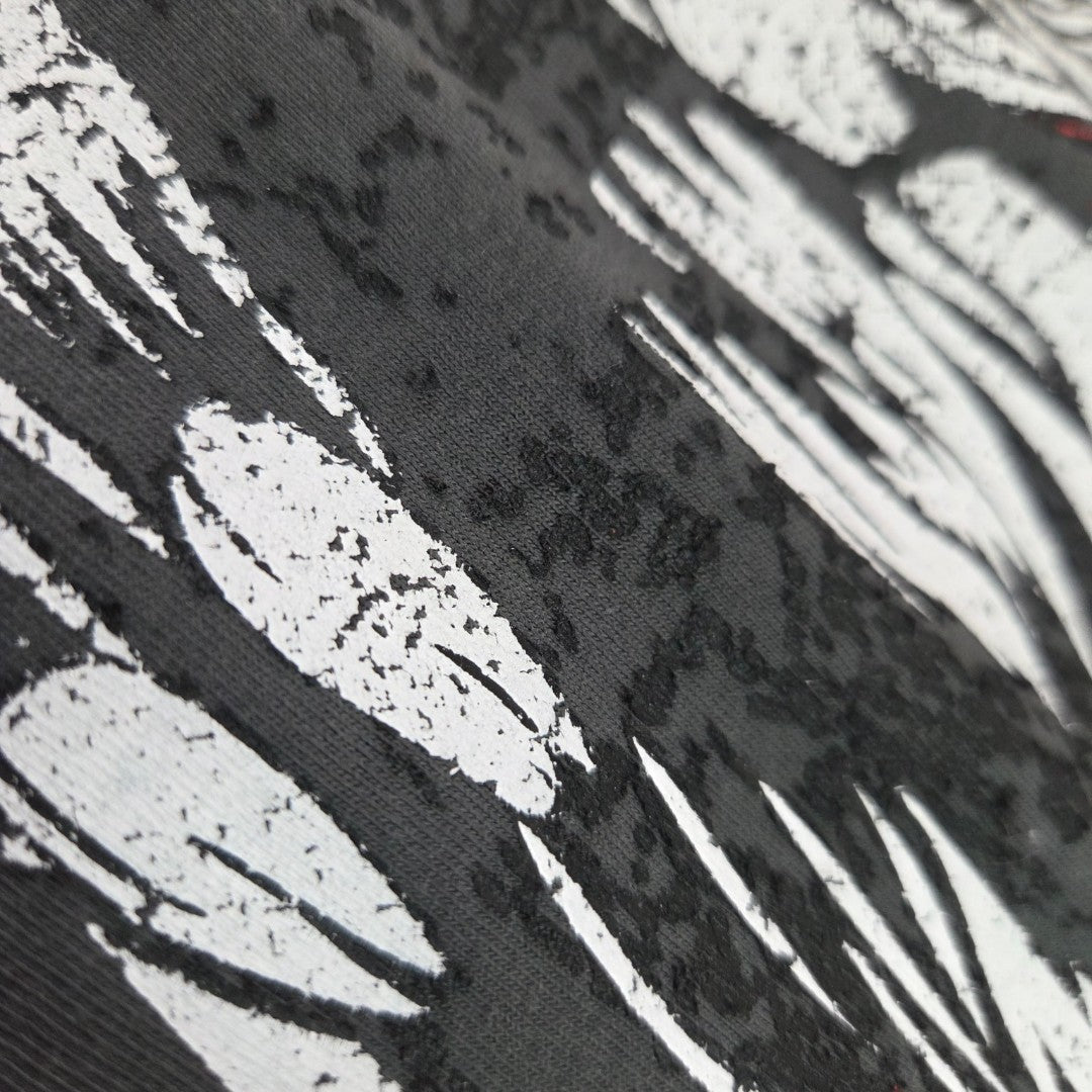 Close-up of the Upcycled Breastfeeding (Nursing) & Pumping Grey Iron Maiden Band t-shirt by George, featuring black fabric with dynamic white, abstract brushstroke patterns and textured, raised black areas—an artistic and affordable UK22 nursing wear choice that beautifully blends style with function.