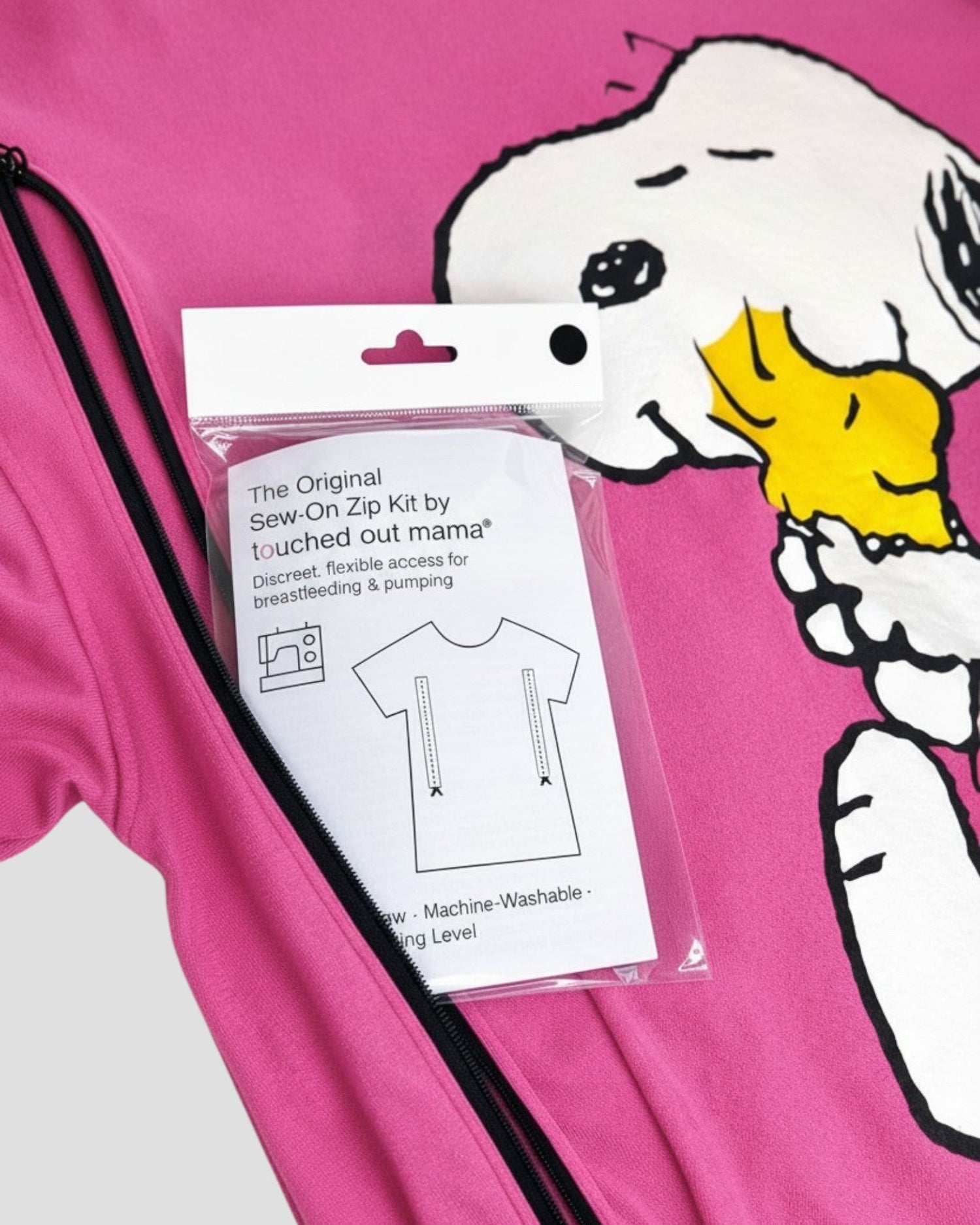 A white product box labeled The Original Sew-On Zip Kit by touched out mama with a shirt graphic and list of needed sewing items, promoting discreet breastfeeding and pumping access.
